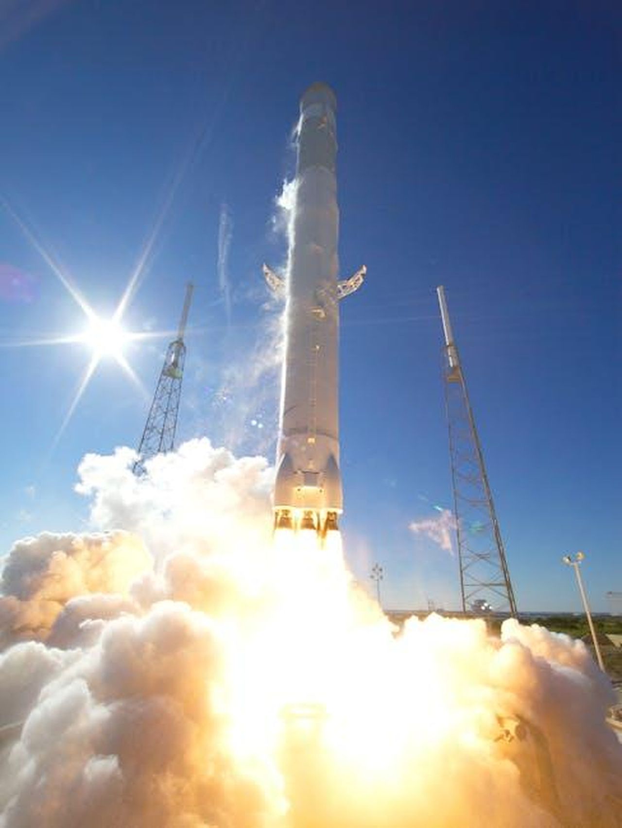 Ulteriore_utilizzo_di_camion_a_motore_a_idrogeno_nel_progetto_HyCET_vnWFt3m9dS - Veicoli24 Source: SpaceX - pexels - A powerful rocket takes off into a clear blue sky, surrounded by clouds of smoke.