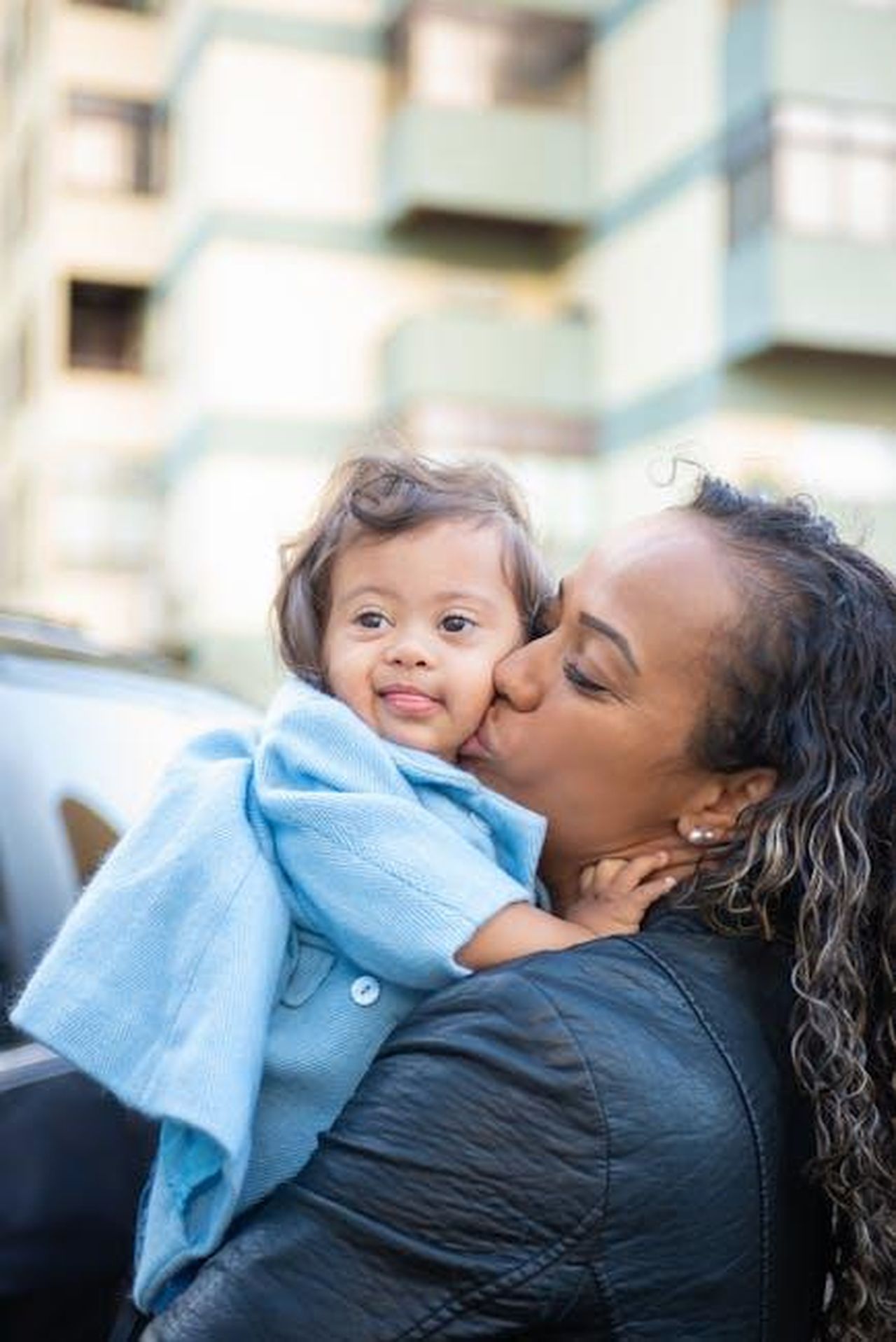 Vantaggi_delle_berline_rispetto_alle_SUV_rK437SPVym - Veicoli24 Source: Kampus Production - pexels - A loving moment of a mother kissing her baby while outdoors, depicting affection and family bond.