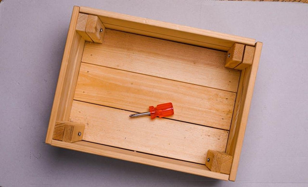 Visita_alla_fabbrica_di_assemblaggio_di_Craftsman_9XKAEFjnIS - Veicoli24 Source: Sergey Meshkov - pexels - Flat lay of a red screwdriver inside an empty wooden box on a gray background.