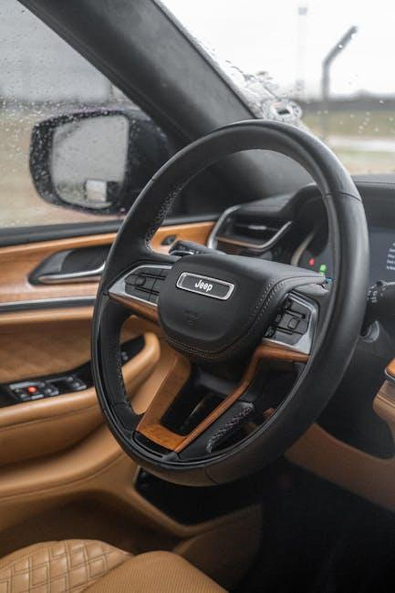 Allestimenti_disponibili_per_lAvenger_4xe_yuSCOqgW6P - Veicoli24 Source: 04iraq - pexels - Close-up of a Jeep steering wheel inside a luxury SUV with raindrops on the window.