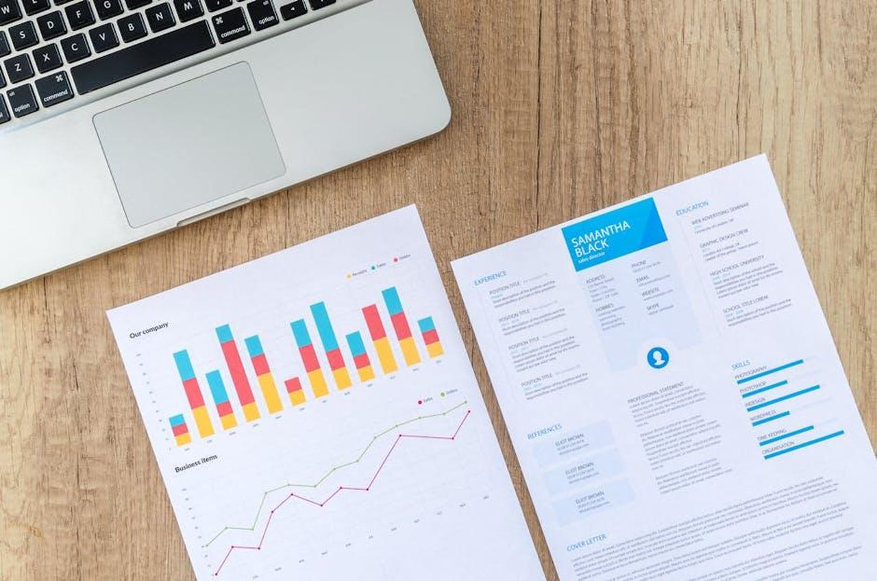 CV_Dr_Nicolai_Martin_1c5em4Mguk - Veicoli24 Source: Lukas - pexels - Top view of a laptop, charts, and resume on a wooden desk, showcasing business analysis and job application.
