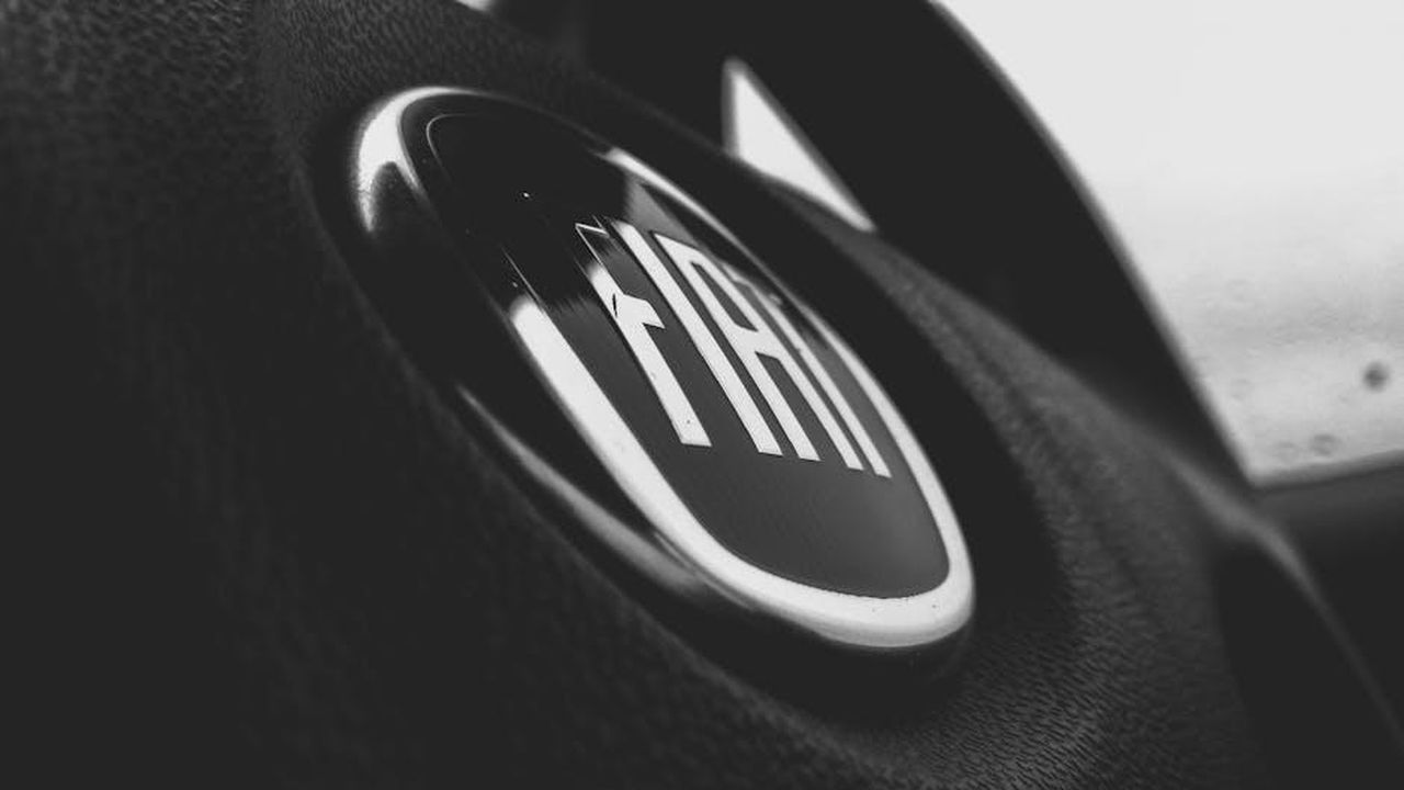 Caratteristiche_e_design_della_Fiat_Grande_Panda_IQSZNfksEp - Veicoli24 Source: Asif Methar - pexels - Detailed black and white image of a Fiat car emblem on a steering wheel interior.