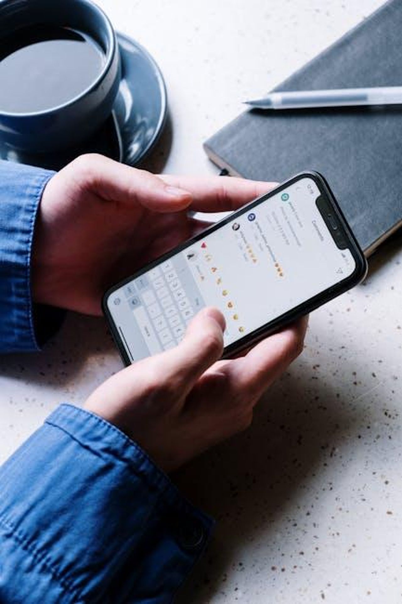 Commenti_dei_dirigenti_R8YiaVSCIh - Veicoli24 Source: cottonbro studio - pexels - Close-up of hands holding smartphone, using chat app. Coffee and notebook nearby indicate casual setting.