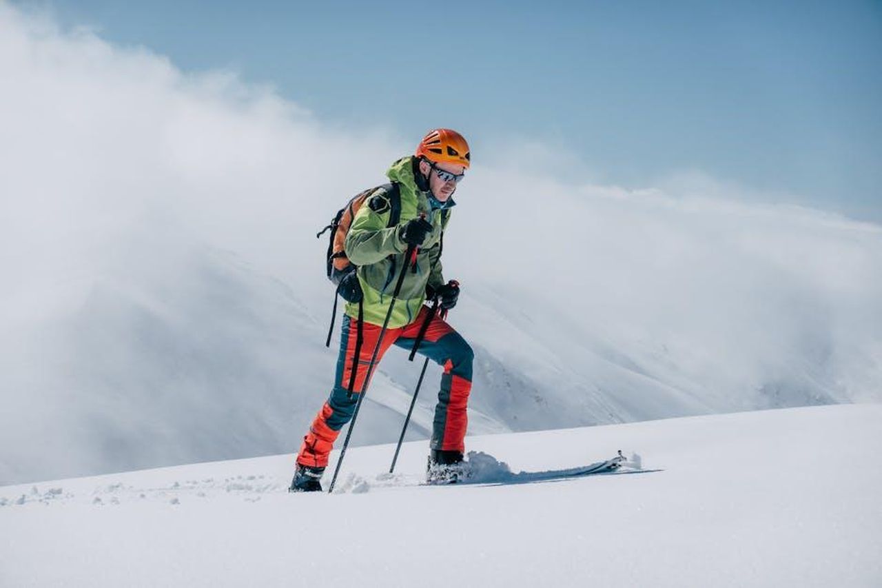 Commenti_di_Aauri_Bokesa_sulla_partnership_GtZone888g - Veicoli24 Source: Jordi Costa Tomé - pexels - A skier trekking uphill on a snowy mountain in bright winter gear, under a clear sky.