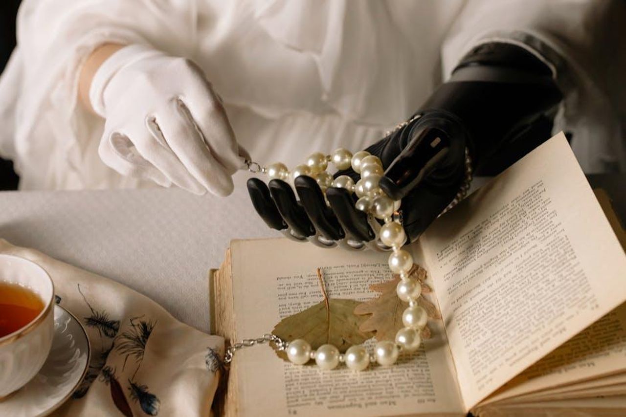Configurazione_ibrida_Q4_gRM9SnVwmQ - Veicoli24 Source: cottonbro studio - pexels - A graceful prosthetic hand holds a pearl necklace over an open book, blending technology and elegance.