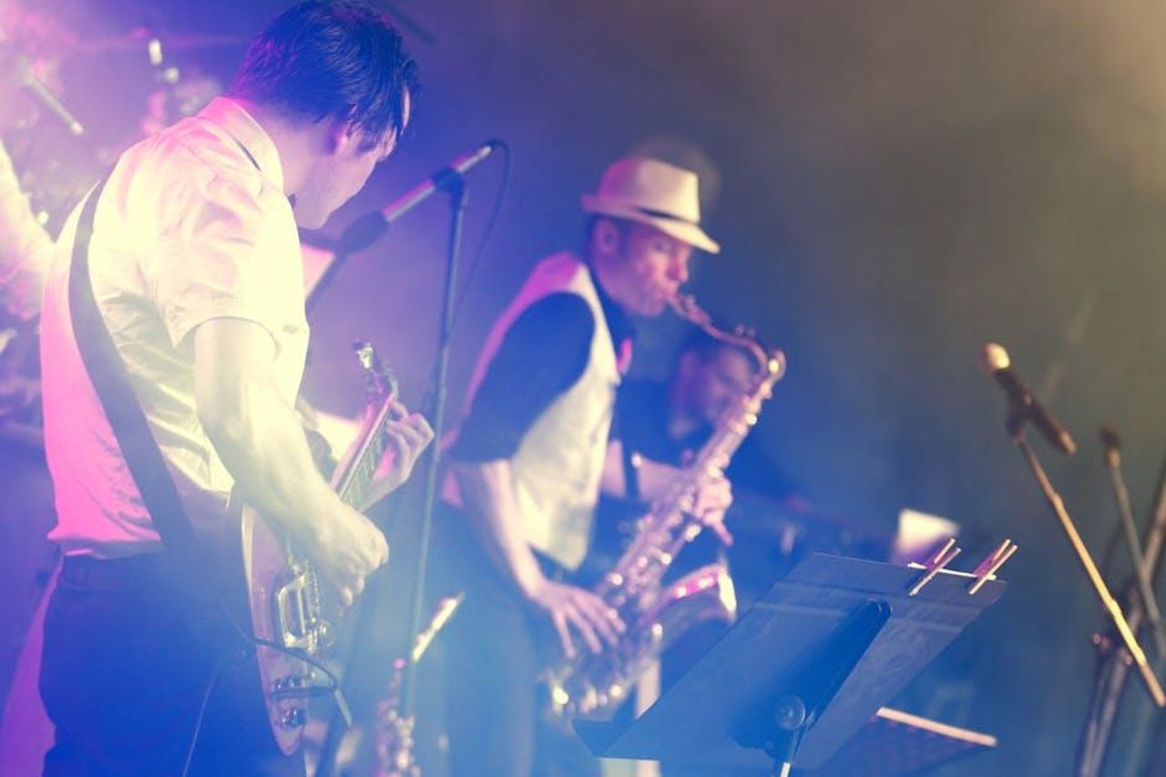 Cool_vibes_e_musica_coinvolgente_BVK9bRI9OZ - Veicoli24 Source: Tuur Tisseghem - pexels - Vibrant stage performance featuring a guitarist and saxophonist at an energetic live concert.