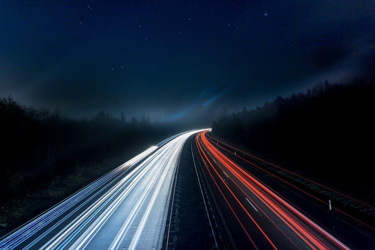 Cosa_ci_piace_Ao71rXAAbJ - Veicoli24 Source: Pixabay - pexels - Long exposure night shot capturing stunning red and white light trails on a highway under a starry sky.