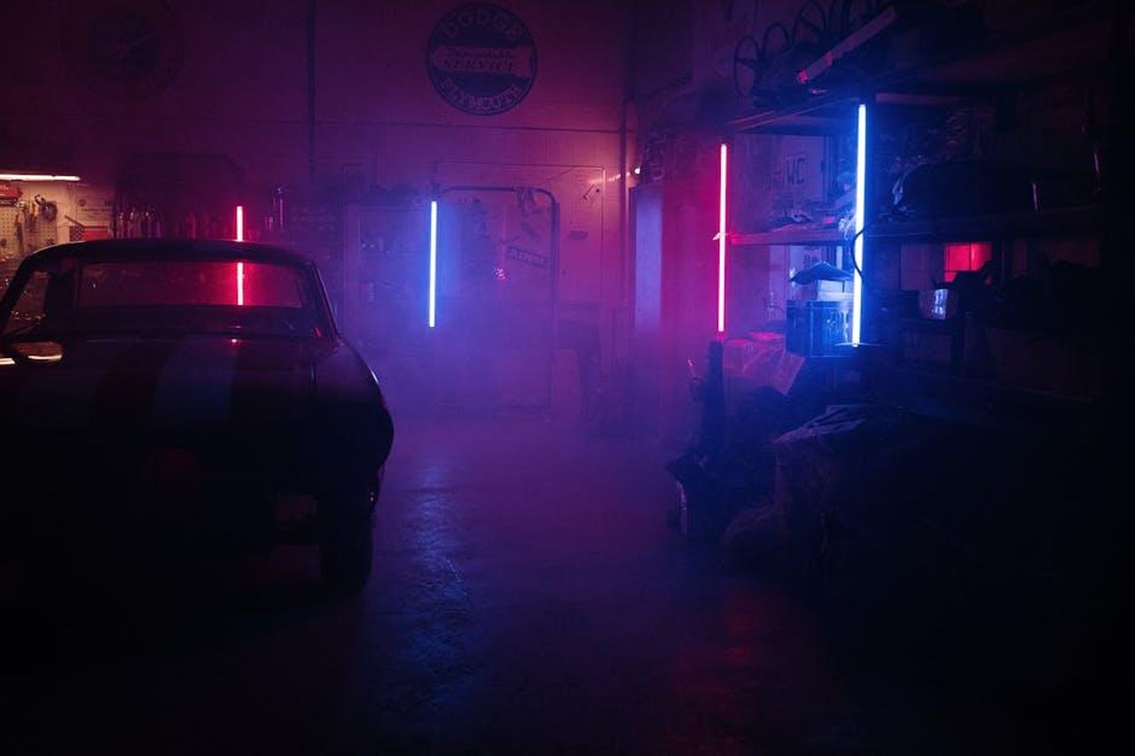 Cosa_non_ci_piace_VFCOnGHxy2 - Veicoli24 Source: cottonbro studio - pexels - Moody garage interior featuring neon lights and a classic car silhouette amidst smoky ambiance.