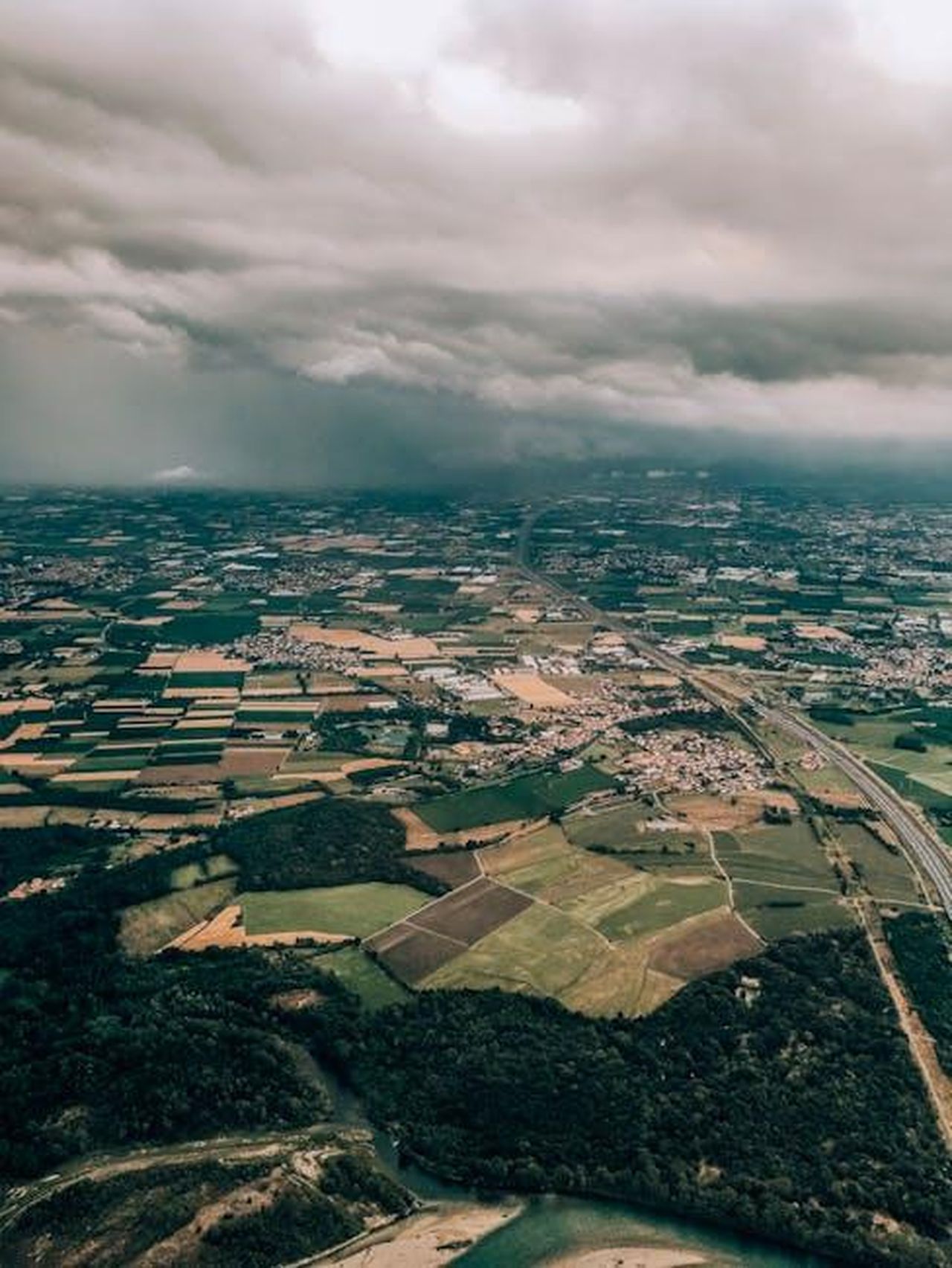 Critiche_alle_nuove_misure_nC43Uuebmh - Veicoli24 Source: Julia Khalimova - pexels - An aerial shot capturing the sprawling farmlands and urban areas of Parona under a dramatic cloudy sky.
