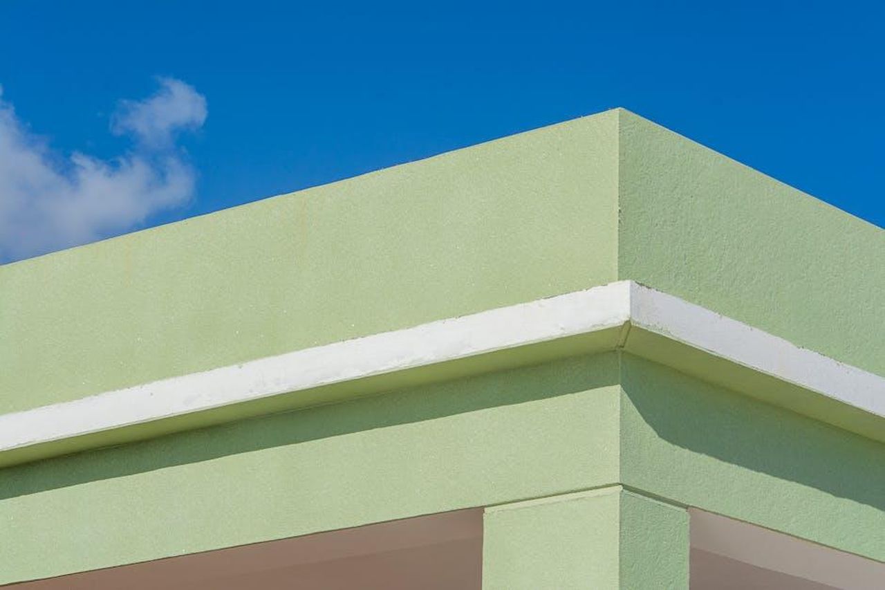 Data_e_luogo_delludienza_2GvSLHwr6H - Veicoli24 Source: Jan van der Wolf - pexels - Angle view of a modern green building facade against a bright blue sky.