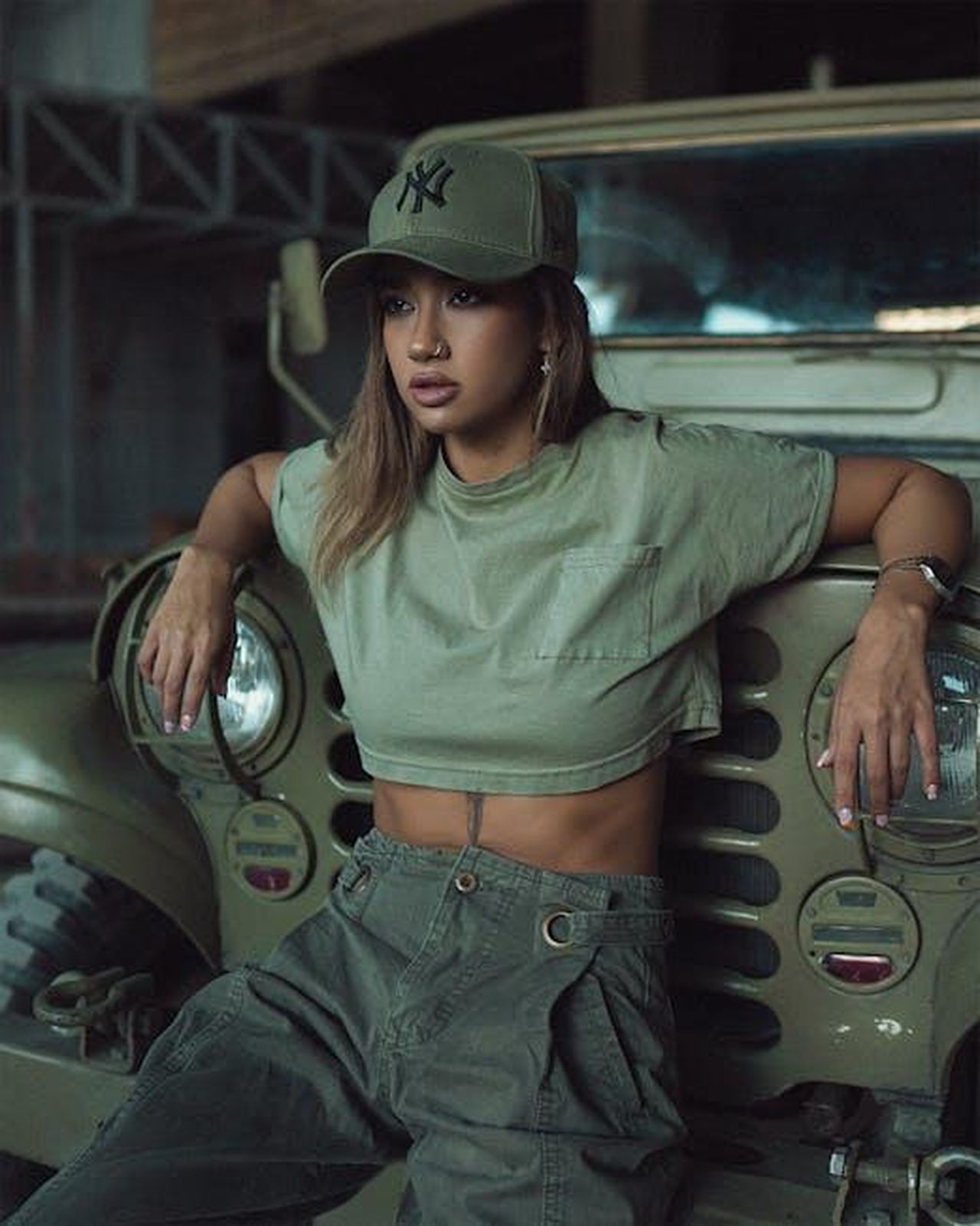 Design_della_Jeep_Avenger_4xe_QYiPllExy4 - Veicoli24 Source: mahdi chaghari - pexels - A fashionable woman in khaki attire leans against a vintage jeep, exuding edgy confidence.