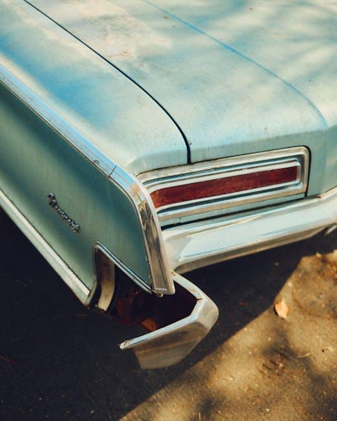 Dettagli_Tecnici_e_Prestazioni_gEC1A0HAGT - Veicoli24 Source: Julian Dahl - pexels - Close-up of a classic blue car showcasing its chrome tail fin and tail lights.