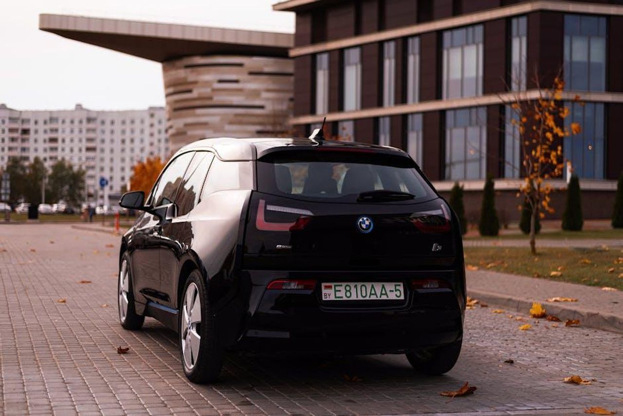 Emissioni_di_CO2_e_consumo_ZJam6fW2dq - Veicoli24 Source: Vitali Adutskevich - pexels - Sleek BMW i3 car parked on a city street with autumn leaves and modern buildings.