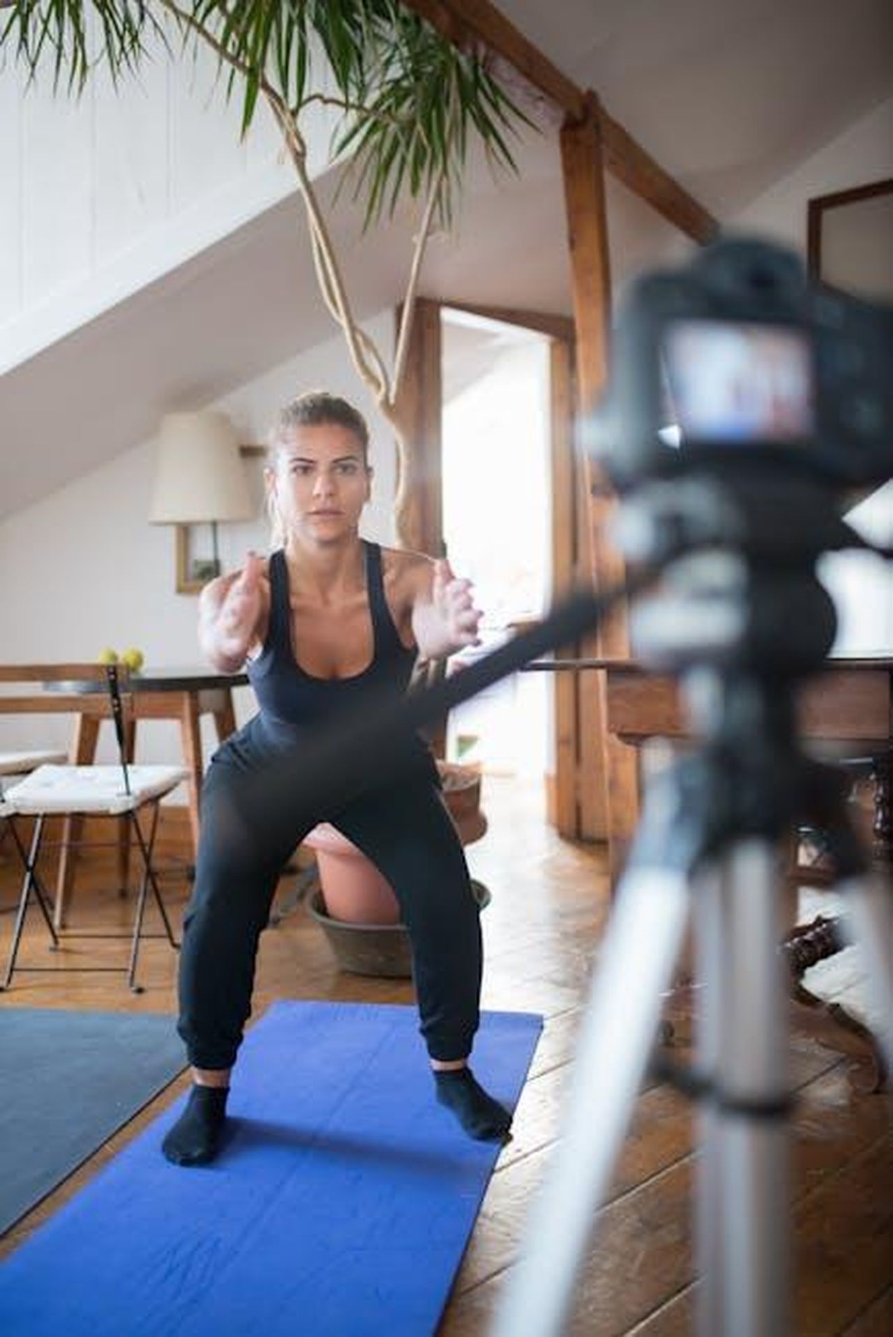Erin_Bourke_Combattere_labuso_online_nello_sport_jmVvmYoTf4 - Veicoli24 Source: Kampus Production - pexels - Young woman performing squats indoors in front of a camera, focusing on fitness training.