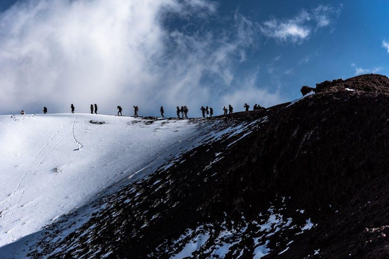 Esplorazione_dellEtna_in_Sicilia_jwC4alN8JT - Veicoli24 Source: Karl K - pexels - Adventurers trekking the snowy slopes of Mount Etna in Sicily, Italy under a dramatic sky.