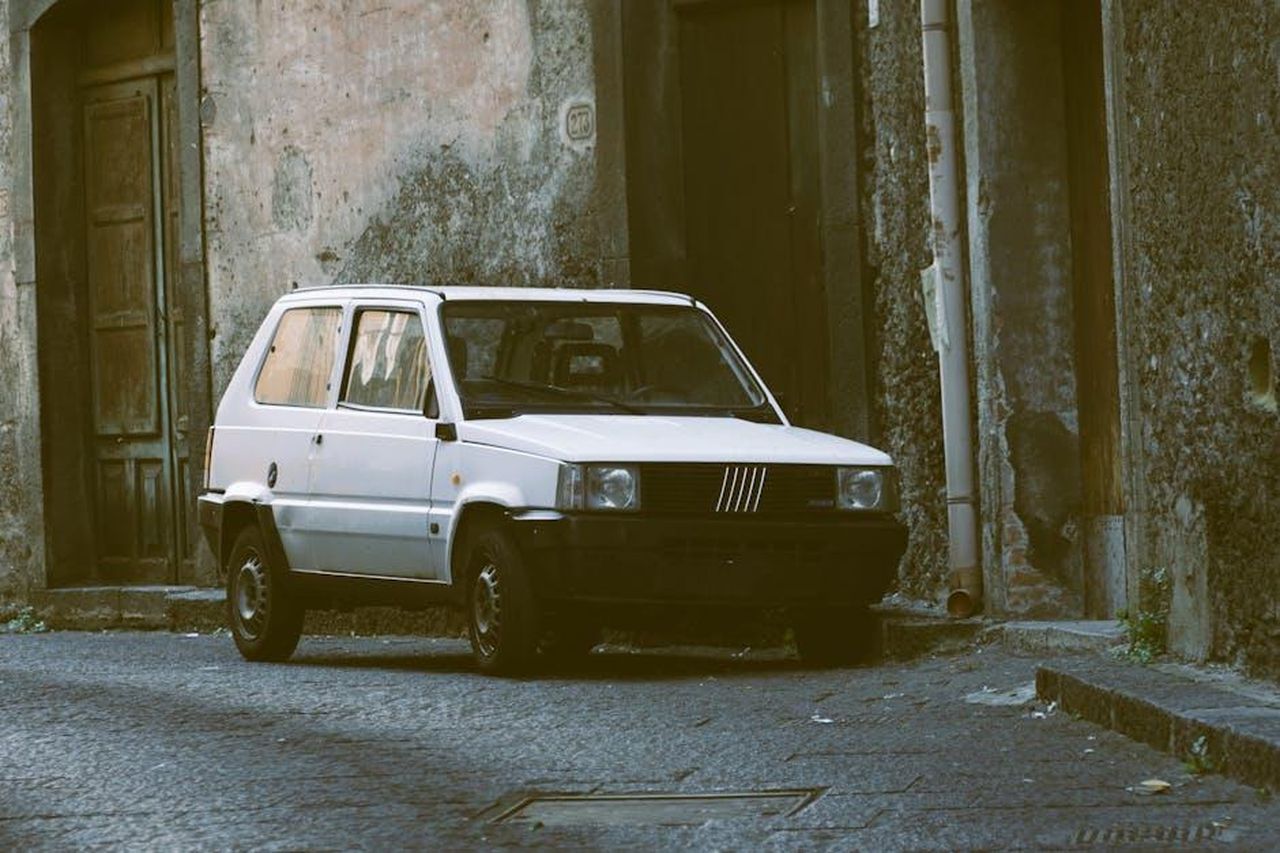 Fiat_Grande_Panda_auto_ufficiale_di_Amici_AOgrETUxLB - Veicoli24 Source: Jan Van Bizar - pexels - A classic white Fiat Panda parked in a narrow urban alley with vintage charm.