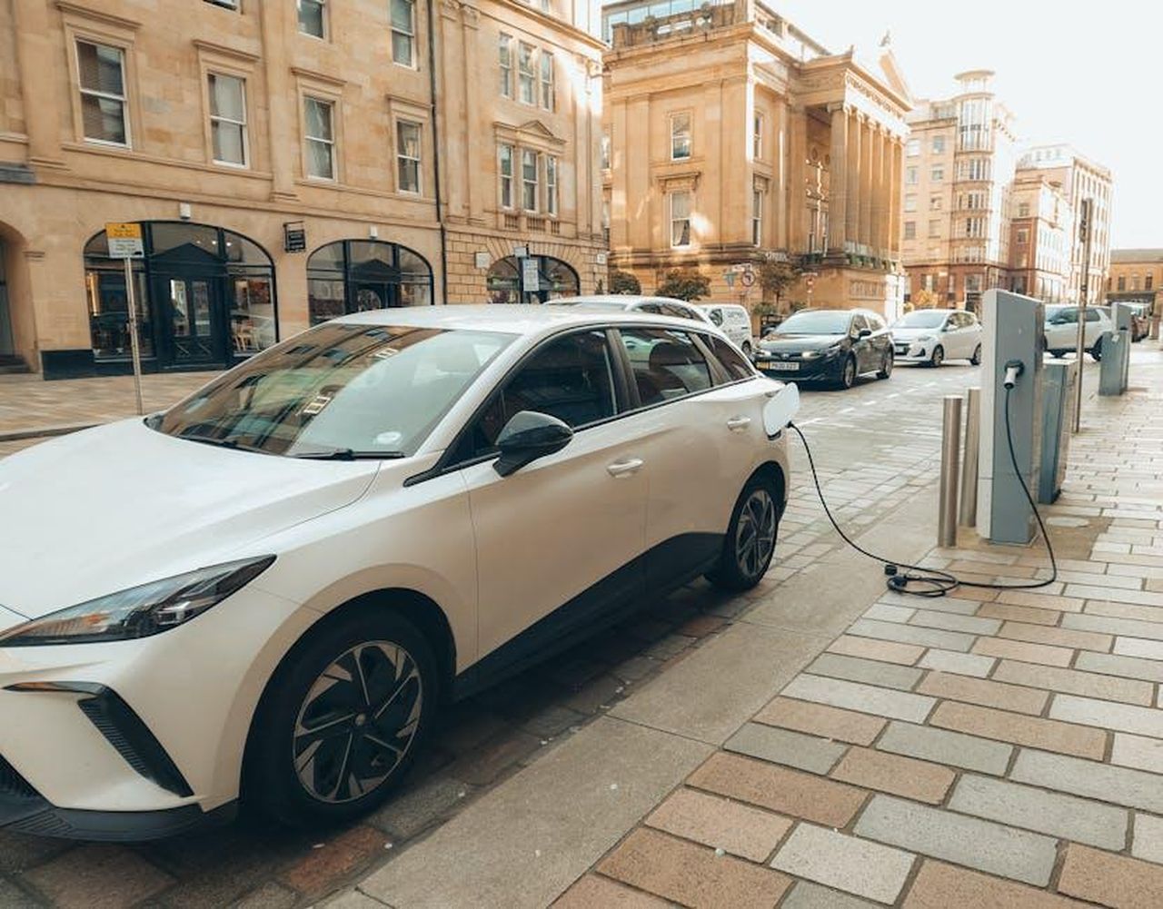 Flessibilit_con_trasmissione_ibrida_a_48_volt_xPfil1ip4Y - Veicoli24 Source: David Gallie - pexels - White electric car charging at a modern station on a Glasgow street.