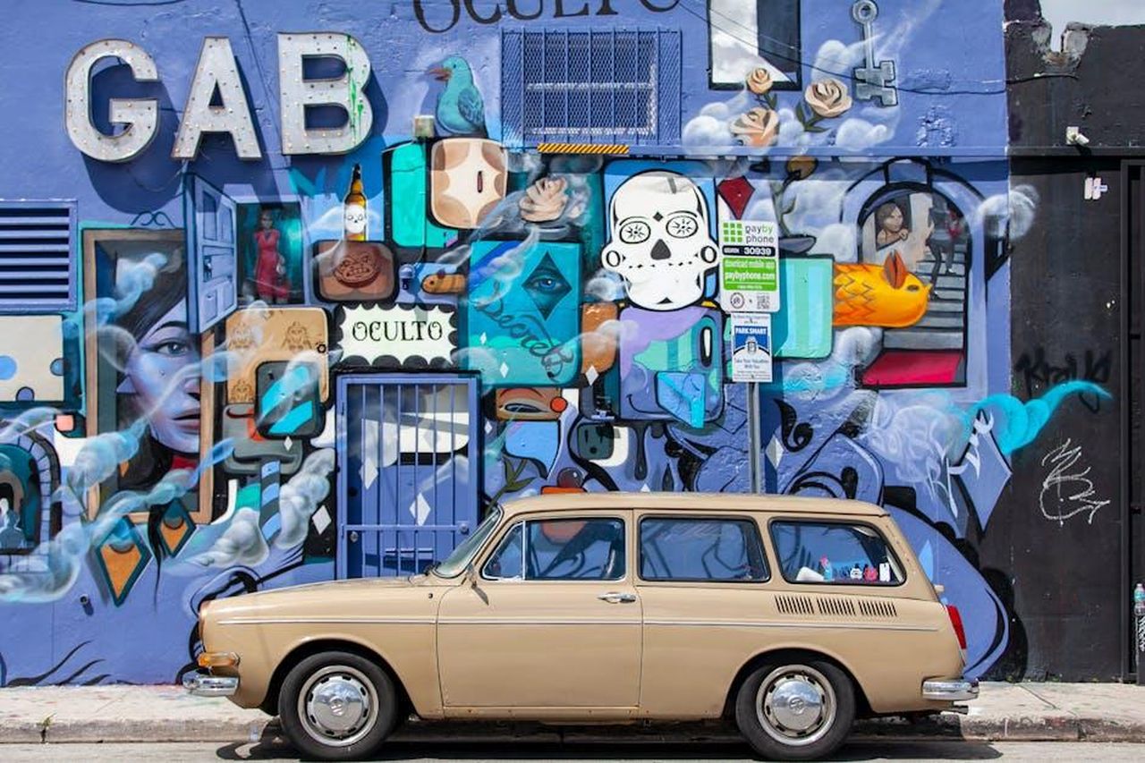 Il_BMW_Art_Car_World_Tour_5LOM01ENTd - Veicoli24 Source: Алексей Васильев - pexels - A vintage car parked against a vibrant street art mural in Miami, Florida.