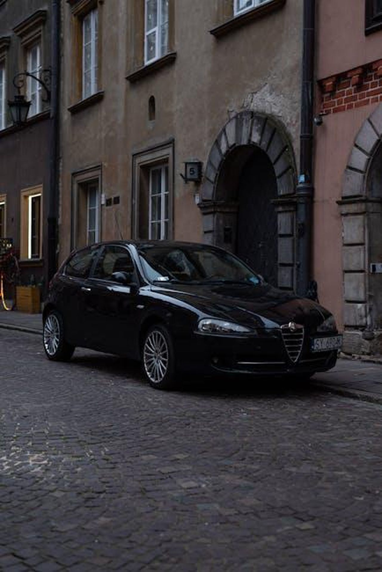 Il_successo_del_modello_Junior_fLmJdpfVMf - Veicoli24 Source: Vitali Adutskevich - pexels - A black Alfa Romeo car parked on a cobblestone street in Warsaw's historic Old Town, Poland.
