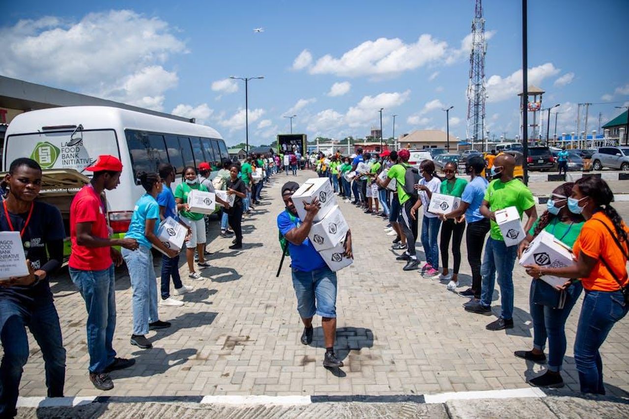 Impatto_della_Collaborazione_BVD2ri1MXO - Veicoli24 Source: Lagos Food Bank Initiative - pexels - Volunteers in bright shirts organize and distribute donation boxes through a human chain outdoors.