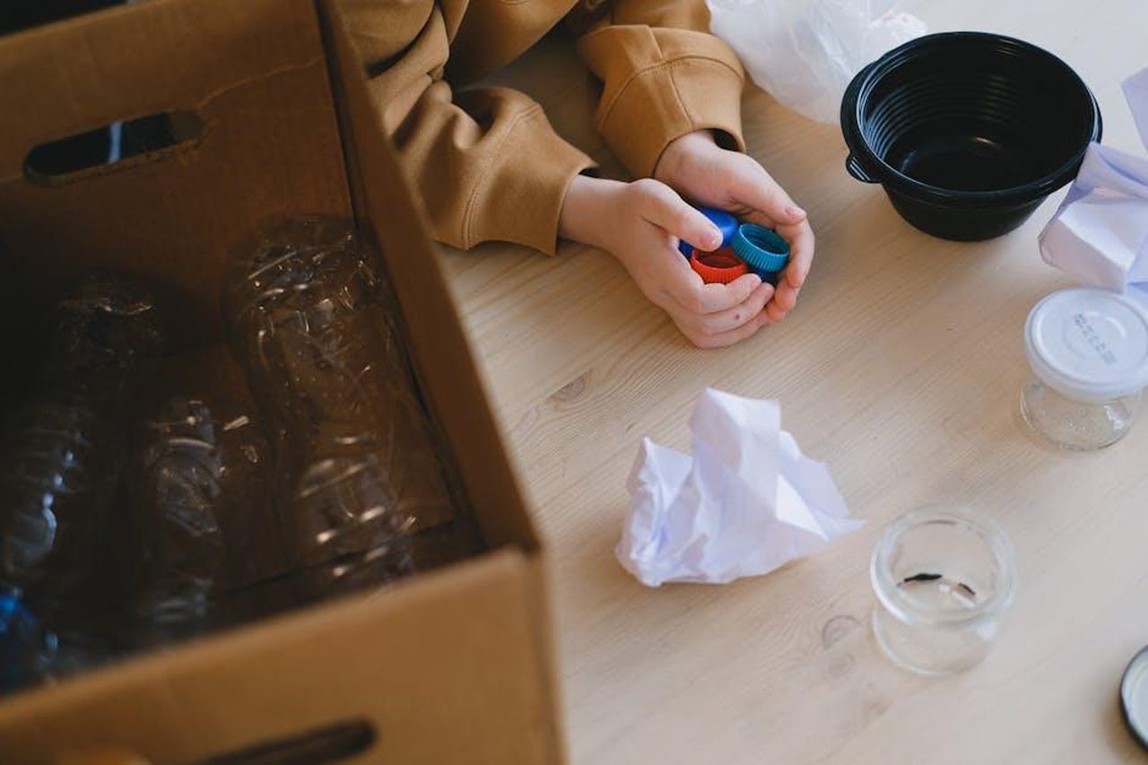 Iniziative_di_Conservazione_delle_Acque_kPrbCbnmNa - Veicoli24 Source: Anna Shvets - pexels - Person organizing recyclable materials like plastic lids and paper on a table.
