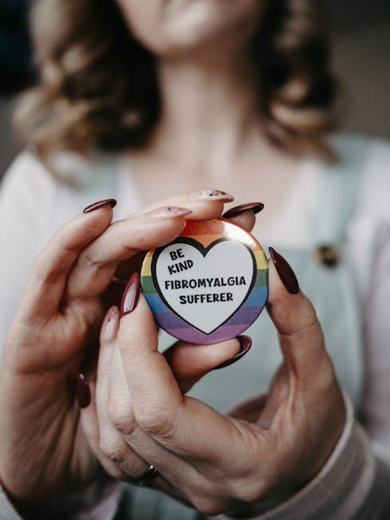 La_campagna_di_sensibilizzazione_di_Lancia_7dxEqJrcM0 - Veicoli24 Source: Lisa from Pexels - pexels - Hands holding a 'Be Kind - Fibromyalgia Sufferer' badge promoting awareness.