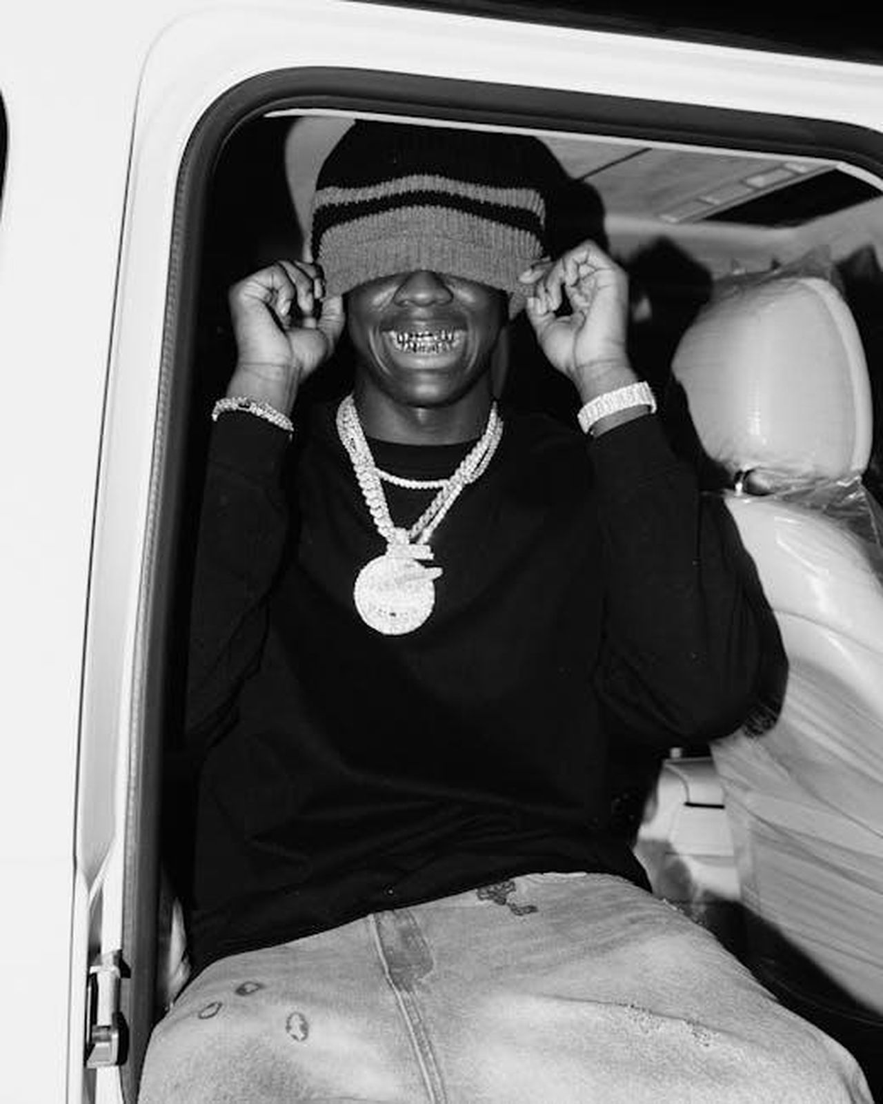 La_collaborazione_tra_FIAT_e_Spotify_fgE9yEfx5w - Veicoli24 Source: Aj Collins Artistry - pexels - Black and white image of a young man in a car, smiling with hat over his eyes.