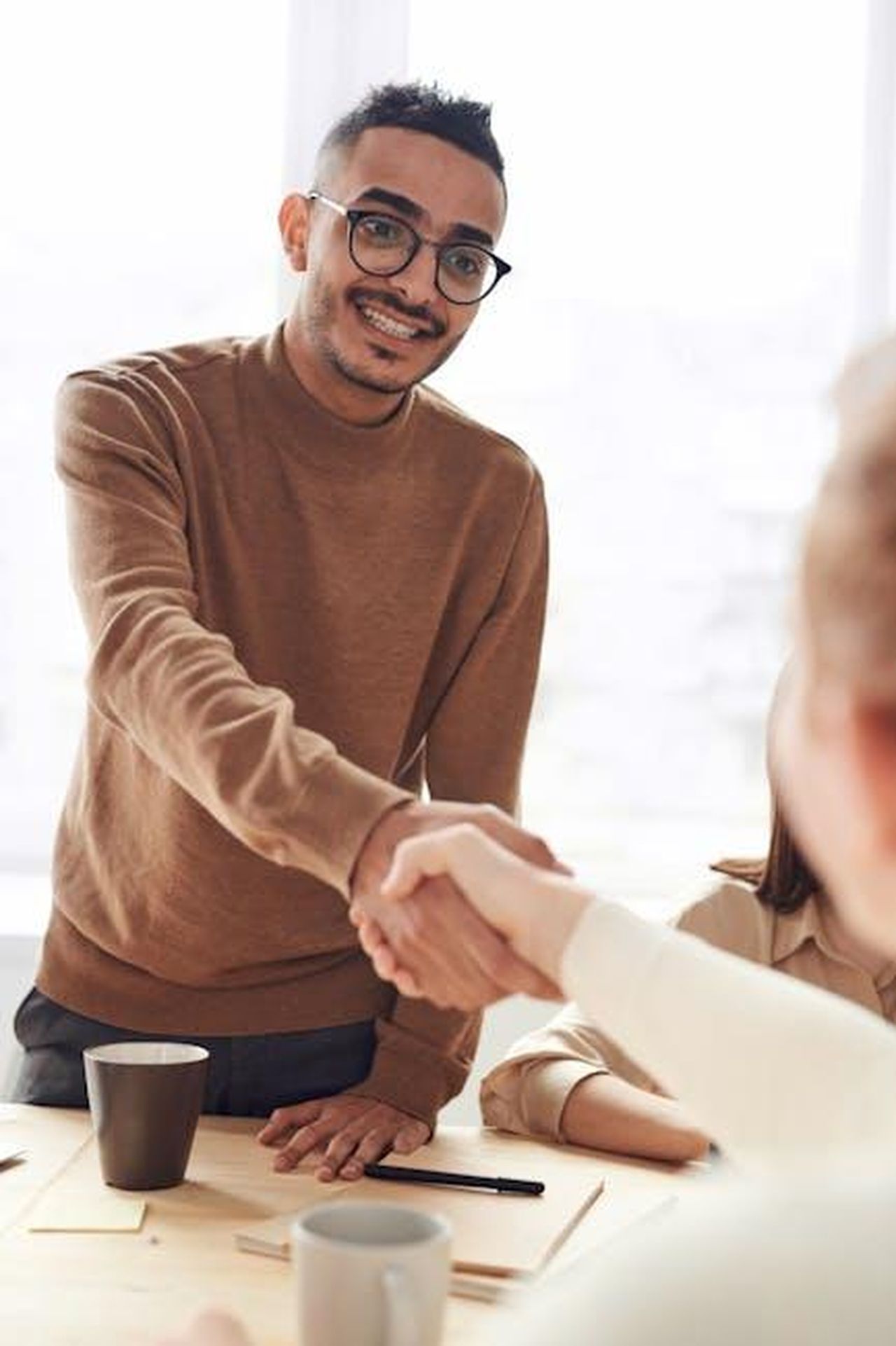 Le_dichiarazioni_dei_leader_di_Shell_e_BMW_M_CbKalLVDMm - Veicoli24 Source: fauxels - pexels - Smiling professionals engage in a welcoming handshake at a business meeting indoors.