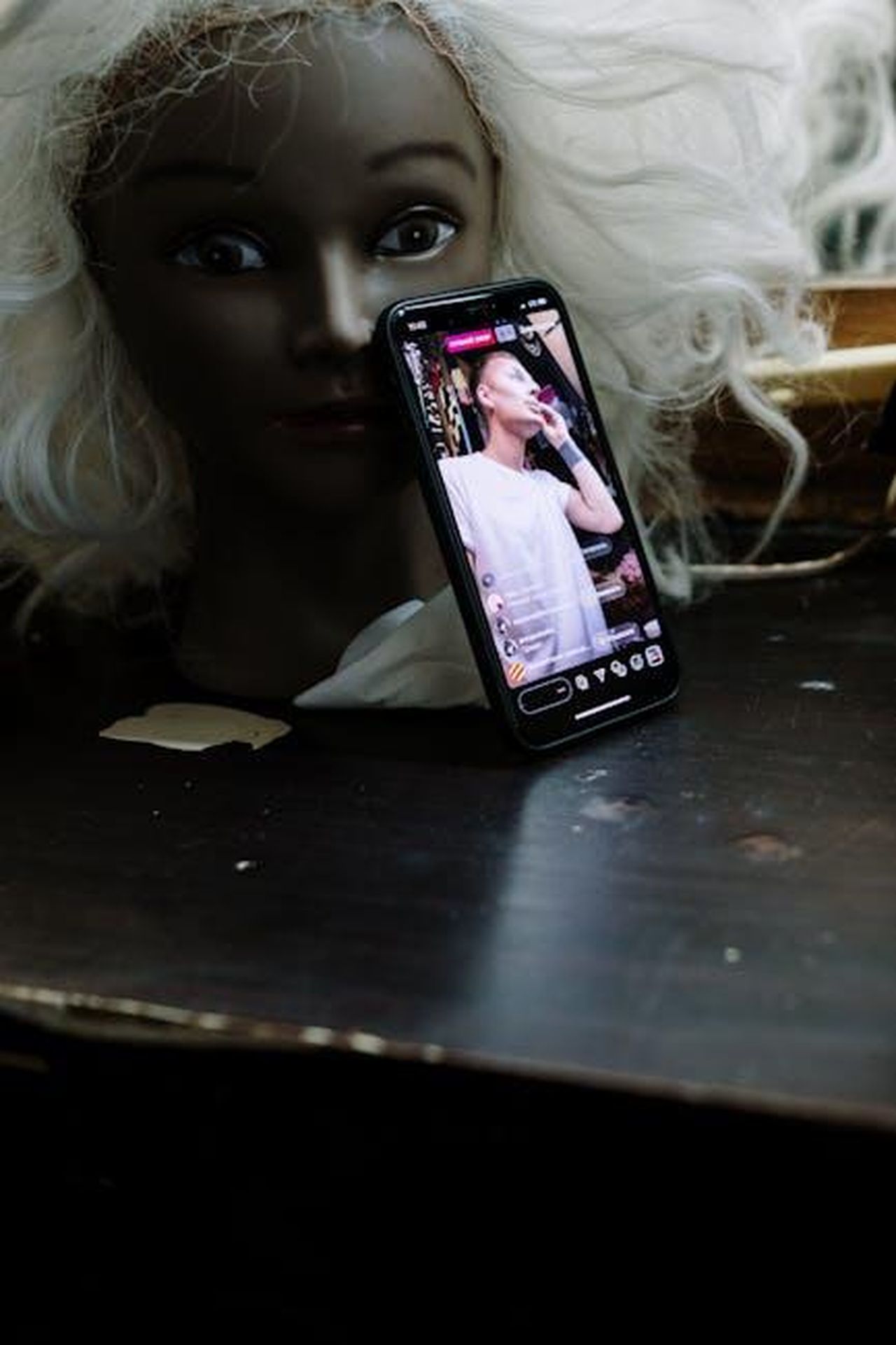 Live_Stream_disponibile_jaiYTICbEO - Veicoli24 Source: cottonbro studio - pexels - Close-up of a mannequin with a smartphone displaying a live makeup stream in a dim indoor setting.