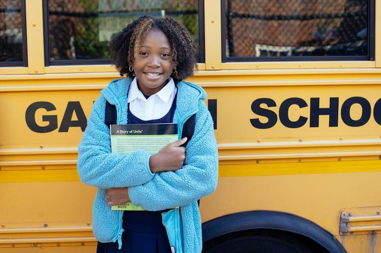 Media_drive_internazionale_di_Junior_Ibrida_Q4_lO8S5i2Aq3 - Veicoli24 Source: Mary Taylor - pexels - Cheerful African American girl in school uniform and warm jacket standing with textbook near yellow school bus and looking at camera