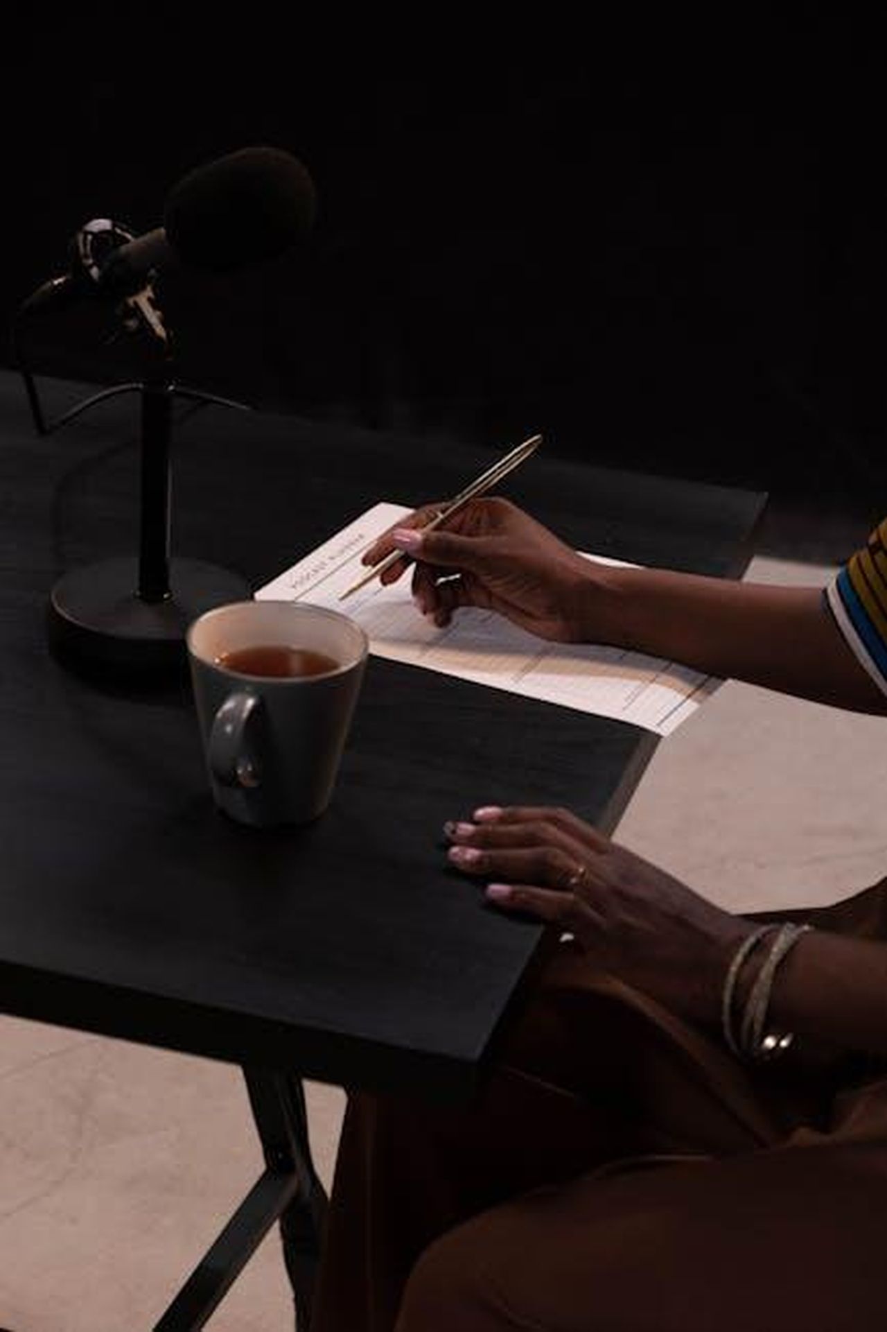 Moderazione_e_relatori_del_talk_yPARw3PwZR - Veicoli24 Source: cottonbro studio - pexels - A person recording a podcast with a microphone, cup of tea, and notes on a table.