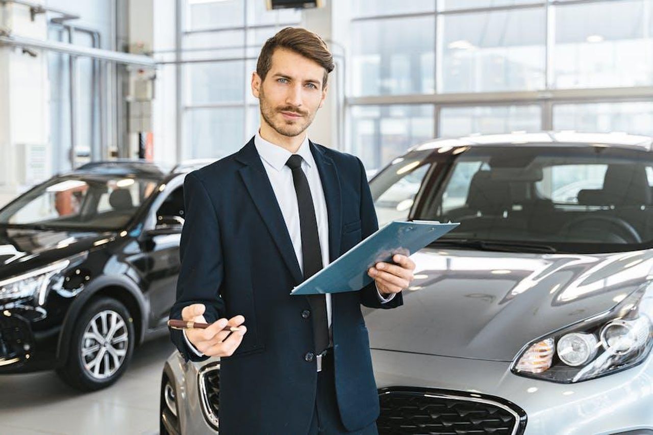 Performance_record_di_BCA_nel_mercato_delle_auto_usate_84oHxClQC9 - Veicoli24 Source: Antoni Shkraba - pexels - Professional car dealer in business suit holding clipboard in a bright car showroom.
