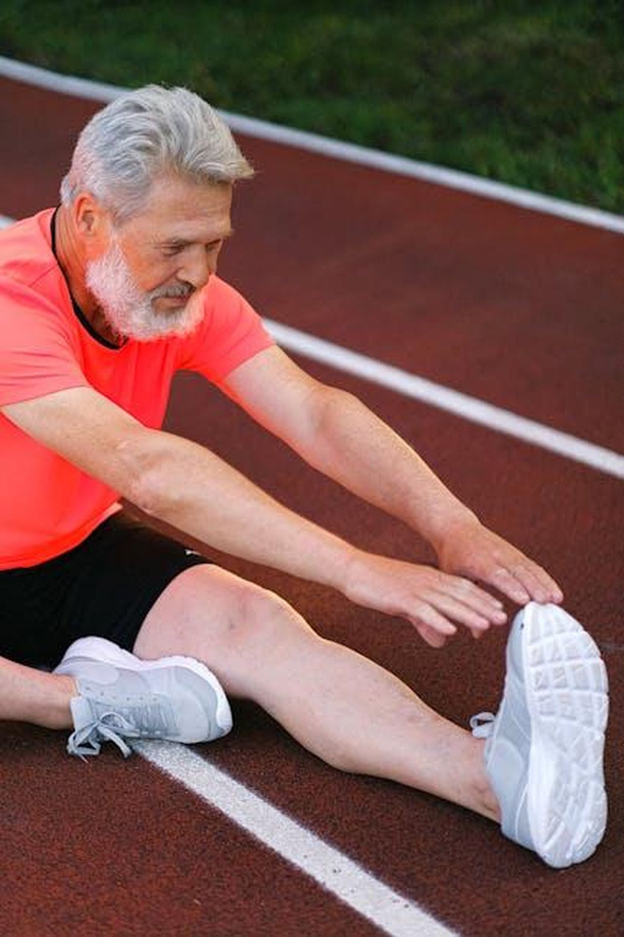 Preparazione_per_la_24h_Nrburgring_zJkon0rTij - Veicoli24 Source: Anna Shvets - pexels - Elderly man stretching and warming up on a running track for exercise.