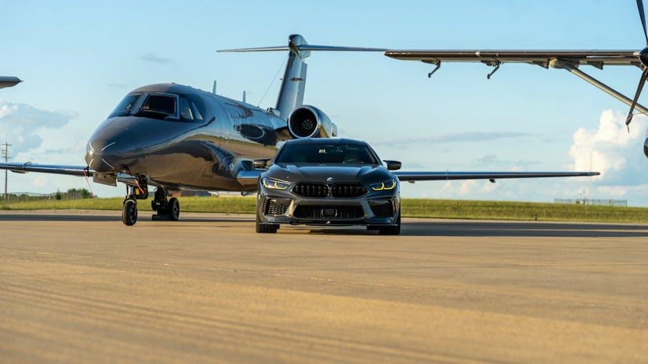 Presentazione_della_20a_BMW_Art_Car_0zqtaIXF3Y - Veicoli24 Source: Harrison Tincher - pexels - A sleek luxury car parked in front of a private jet on a runway, capturing opulence.