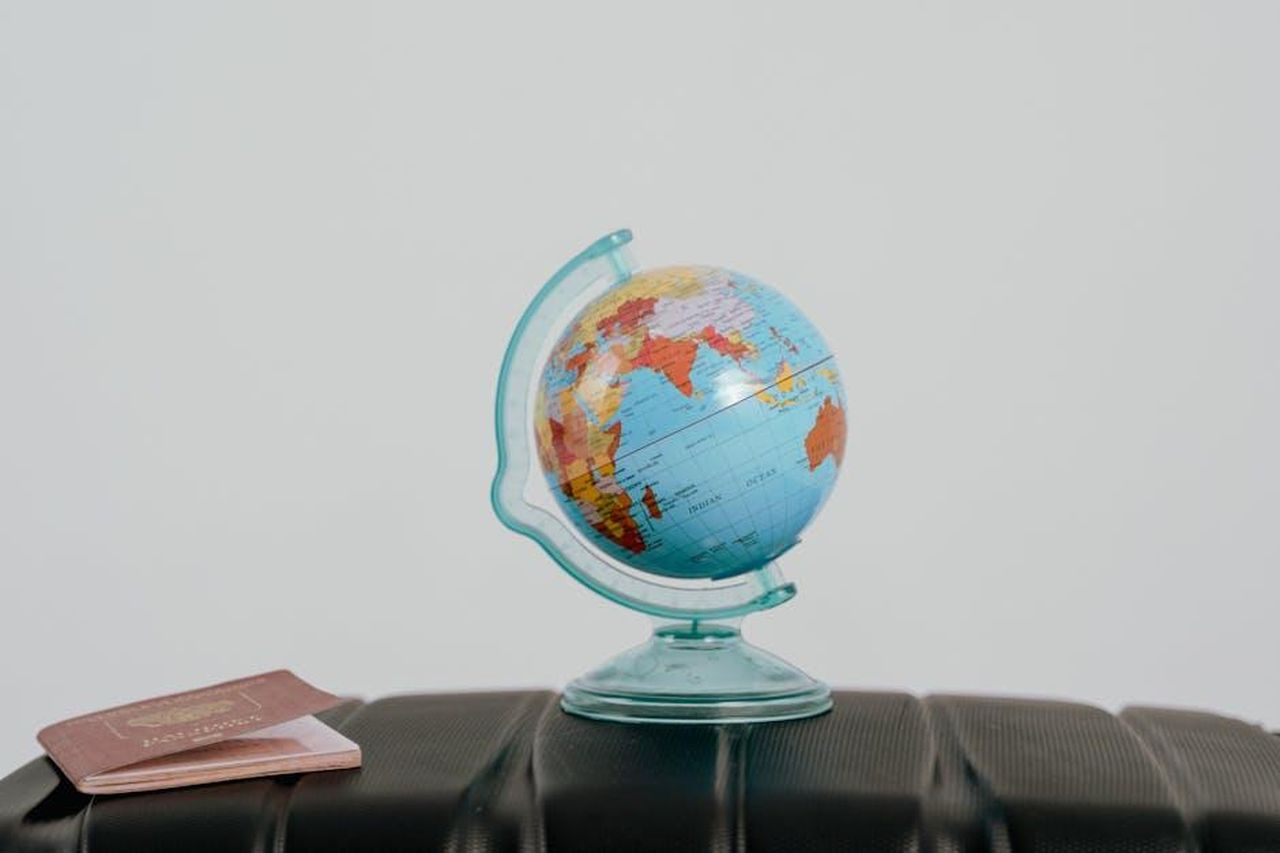 Presenza_Globale_e_Resilienza_f12a1dNIPc - Veicoli24 Source: Tima Miroshnichenko - pexels - A globe and passport on a suitcase, symbolizing travel planning and wanderlust.