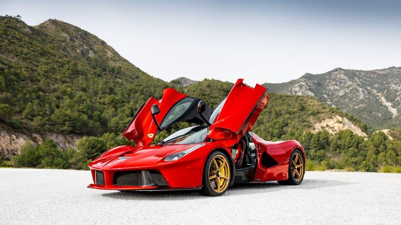 Punti_di_forza_della_Junior_Ibrida_Q4_iOsewxIluE - Veicoli24 Source: Quentin Martinez - pexels - A striking red sports car with open doors against a serene mountain backdrop.