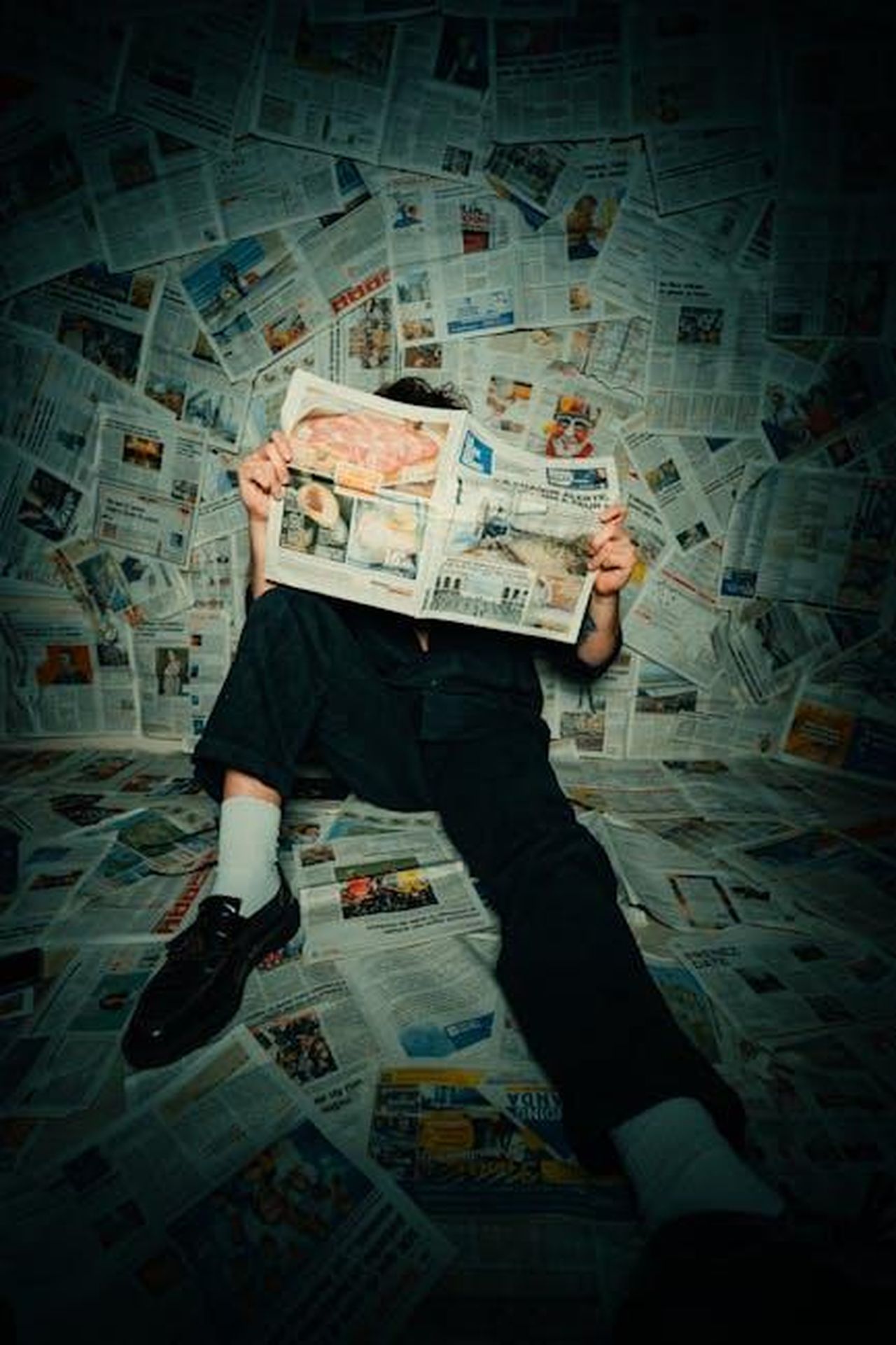 Richiesta_di_accreditamento_per_la_stampa_t5zT3yoKCi - Veicoli24 Source: Léo Gilmant - pexels - Person sitting on floor covered with newspapers, reading in a creative setup.