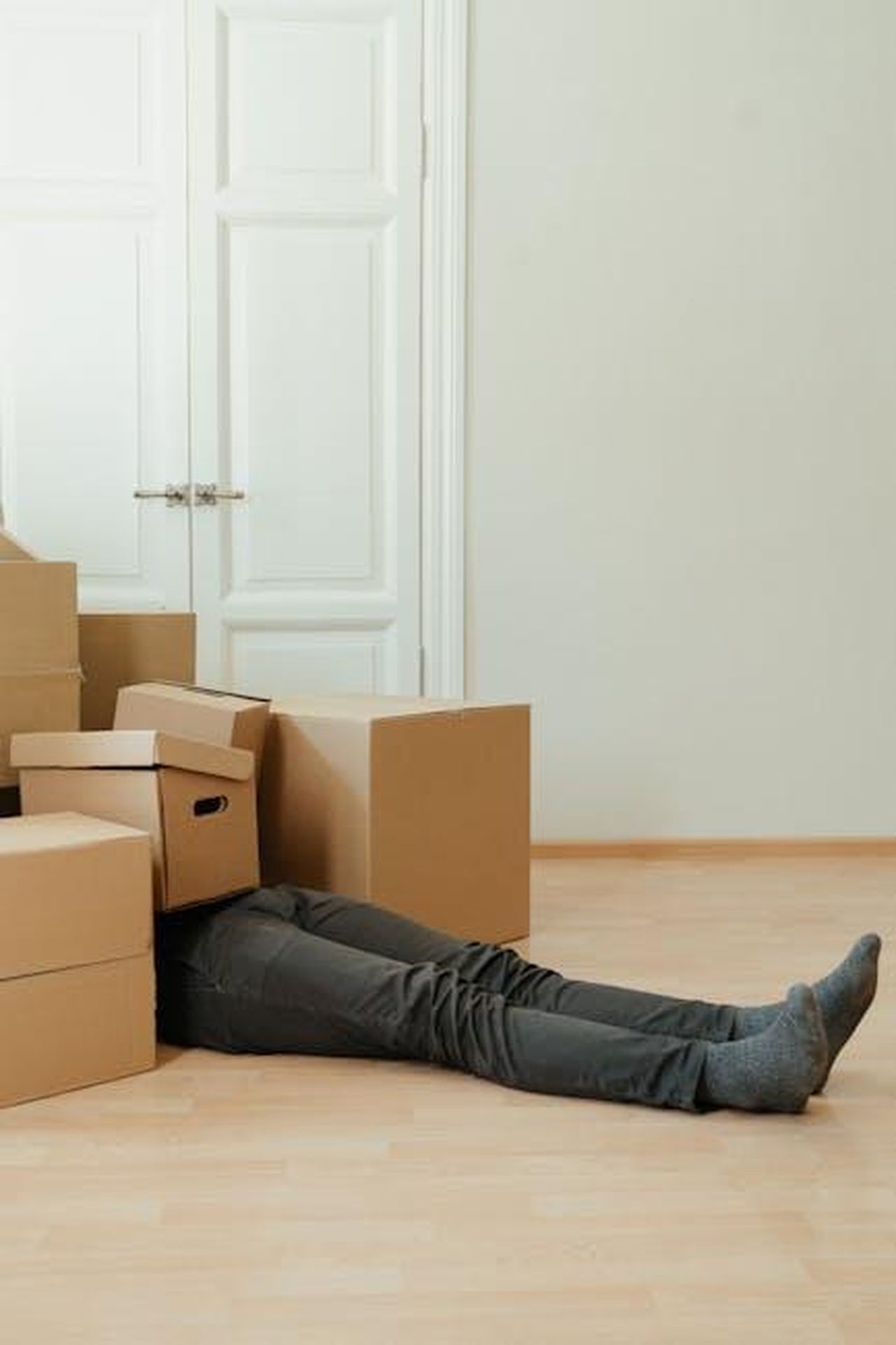 Ruolo_di_Christopher_Yang_come_senior_advisor_NRM80xSe0m - Veicoli24 Source: cottonbro studio - pexels - Man lying tired under cardboard boxes in an empty room, symbolizing moving stress.