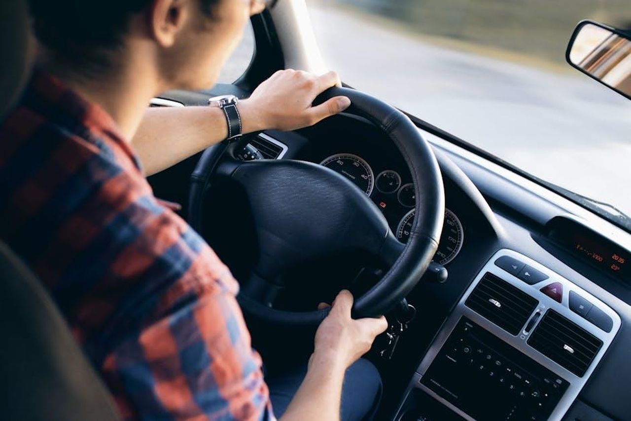 Scuola_Guida_di_Cambio_Automatico_yLbnkDaNV3 - Veicoli24 Source: JESHOOTS.com - pexels - Close-up view of a man driving a modern car, showing dashboard and steering details.