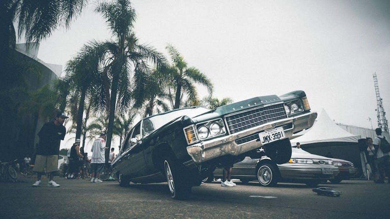 Selettore_DNA_e_massimo_comfort_di_guida_eS4iJd12l3 - Veicoli24 Source: Kaique Rocha - pexels - A vibrant lowrider car with palm trees and people at an outdoor car show.