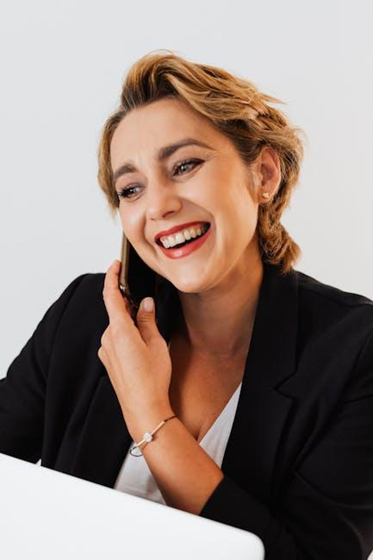 Servizi_connessi_e_vantaggi_cVYRi36k6l - Veicoli24 Source: Photo By: Kaboompics.com - pexels - Professional smiling woman in suit talking on phone, showcasing modern business communications.