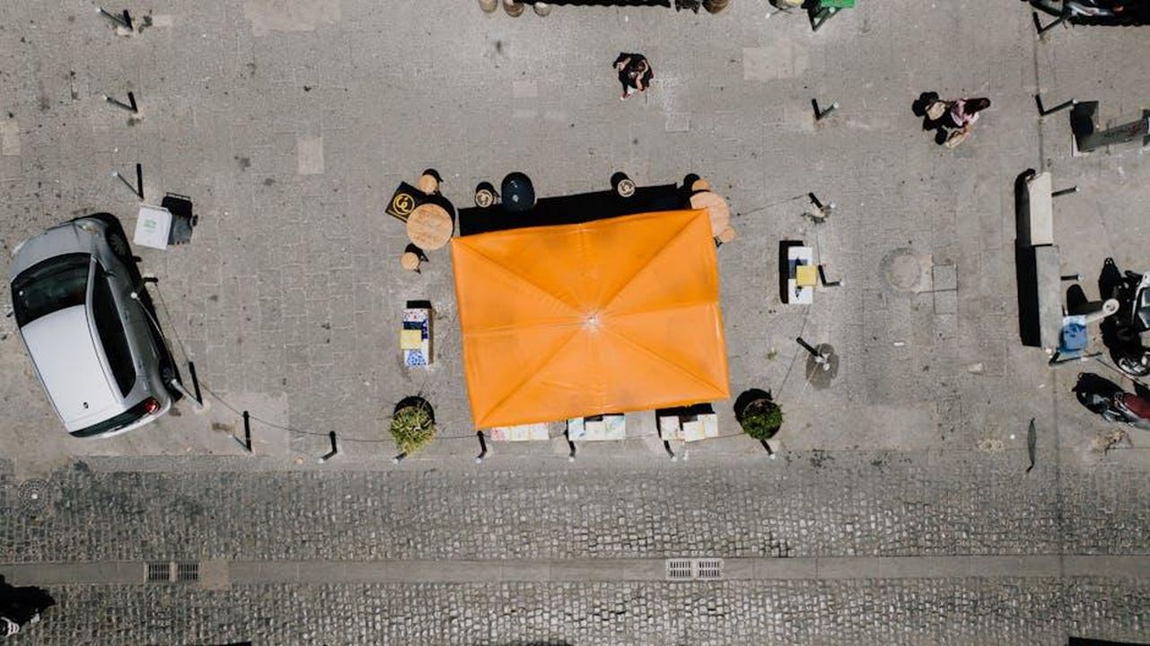 Situazione_del_mercato_in_Italia_EjRSLEfalK - Veicoli24 Source: Kelly - pexels - Top view of a vibrant street cafe with orange canopy in Napoli, Italy.