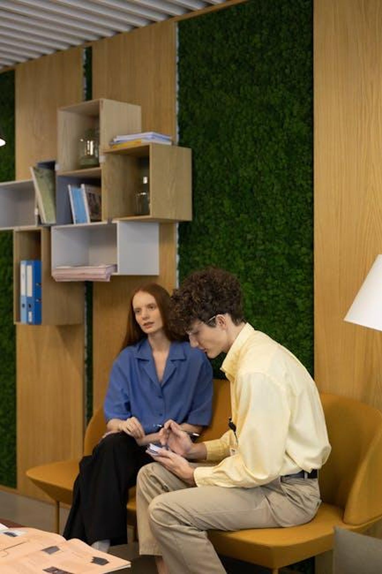 Strategia_aziendale_sostenibile_sei_aree_di_focus_9rufKTR82r - Veicoli24 Source: cottonbro studio - pexels - Two professionals discussing work in a modern office with a green wall feature.