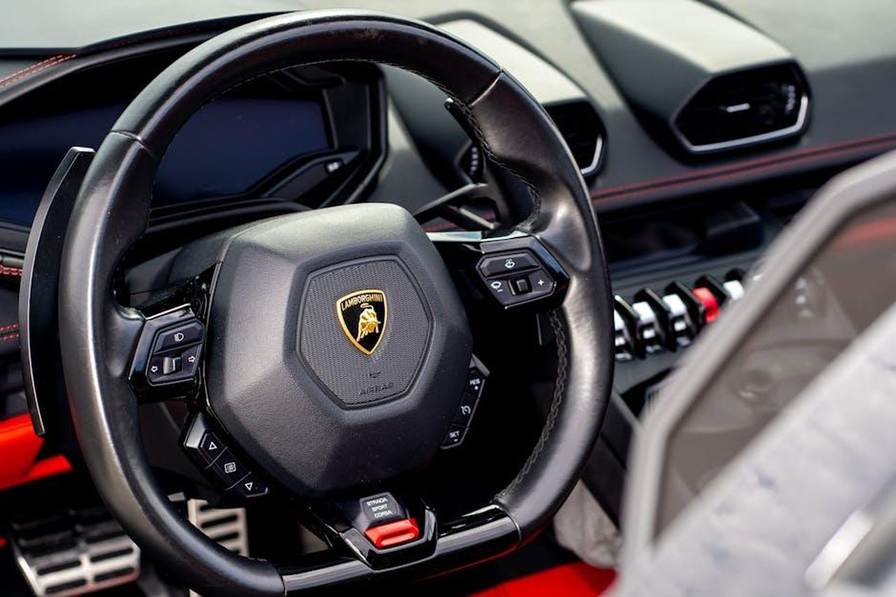 Tecnologia_del_Cambio_EasyDrive_xnujM6j1UT - Veicoli24 Source: Styves Exantus - pexels - Intricate close-up view of a Lamborghini steering wheel showcasing luxury car design.