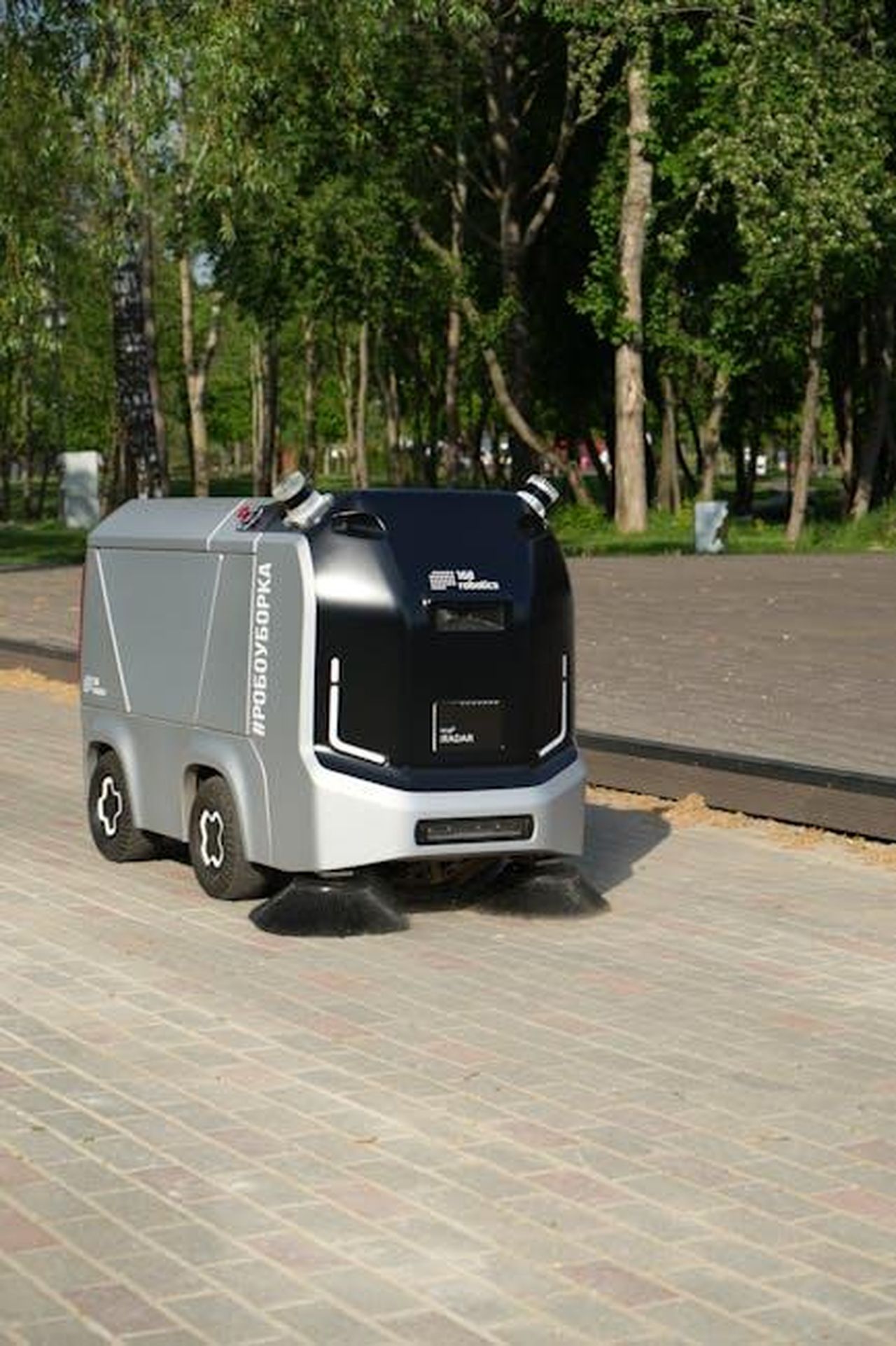 Tecnologia_e_innovazione_M2MqA7hC5j - Veicoli24 Source: Ярослав Сапрыкин - pexels - A robotic street sweeper operates autonomously on a city pavement under sunny conditions.