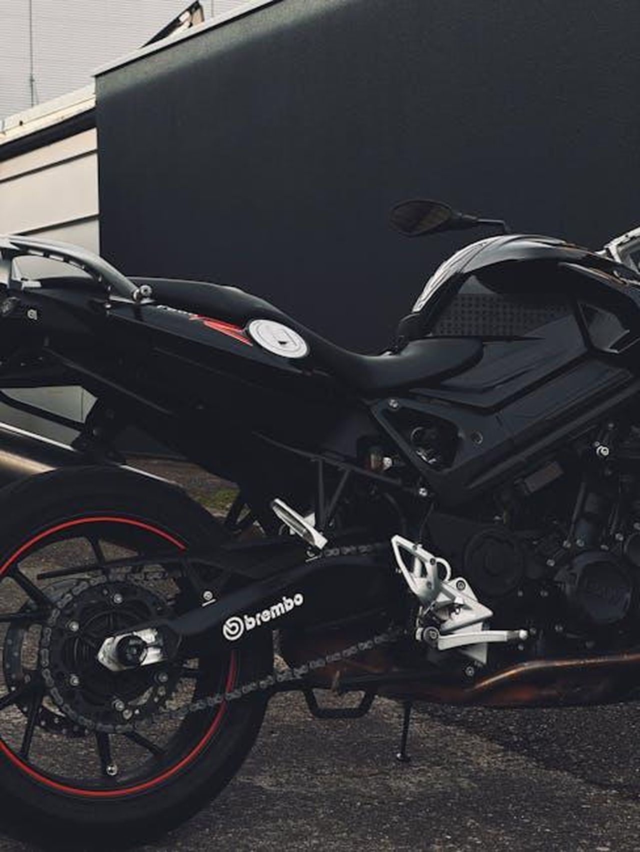 Telaio_in_acciaio_tubolare_e_sospensioni_avanzate_WxrsTWUBfV - Veicoli24 Source: Andreas Ebner - pexels - Close-up of a black motorcycle featuring Brembo brakes in an urban setting.