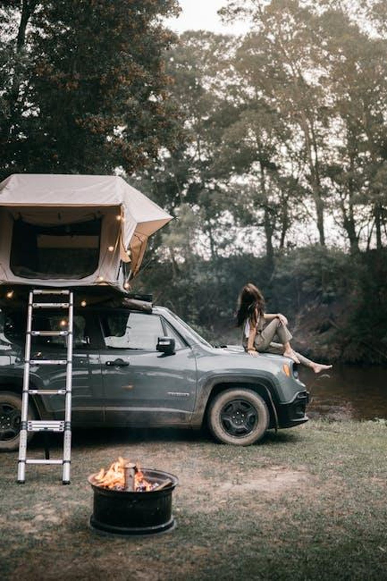 Una_gamma_capace_di_offrire_esperienze_uniche_jqNPz6at1S - Veicoli24 Source: Taryn Elliott - pexels - A woman sits on a jeep by a campfire, enjoying an outdoor adventure.