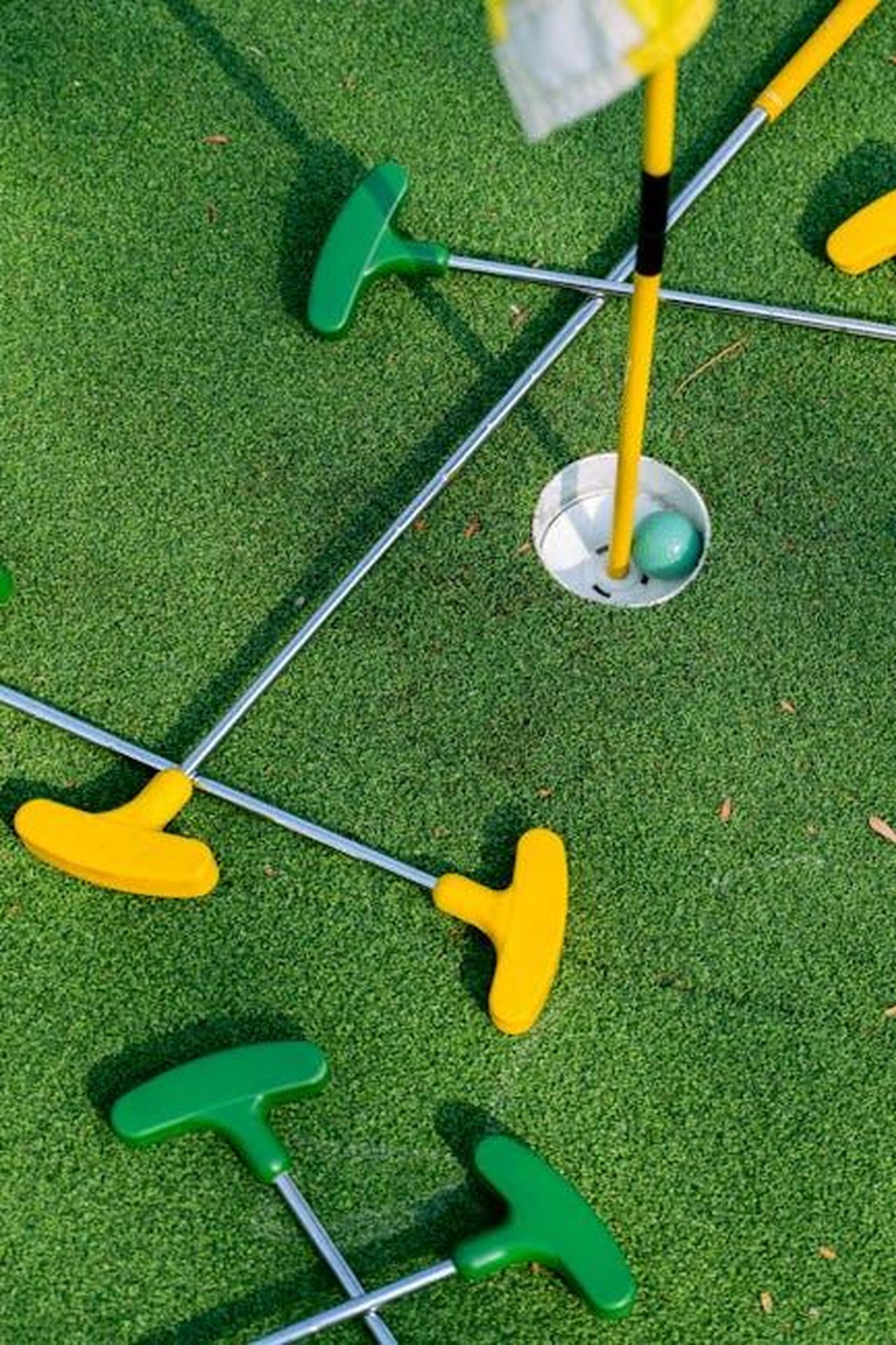 Vietnam_prevale_allAlpine_Golf_Club_con_116000_euro_per_UNICEF_z50o6Kk0FB - Veicoli24 Source: Anna Tarazevich - pexels - Colorful mini golf putters arranged around a hole on a vibrant green putting surface.