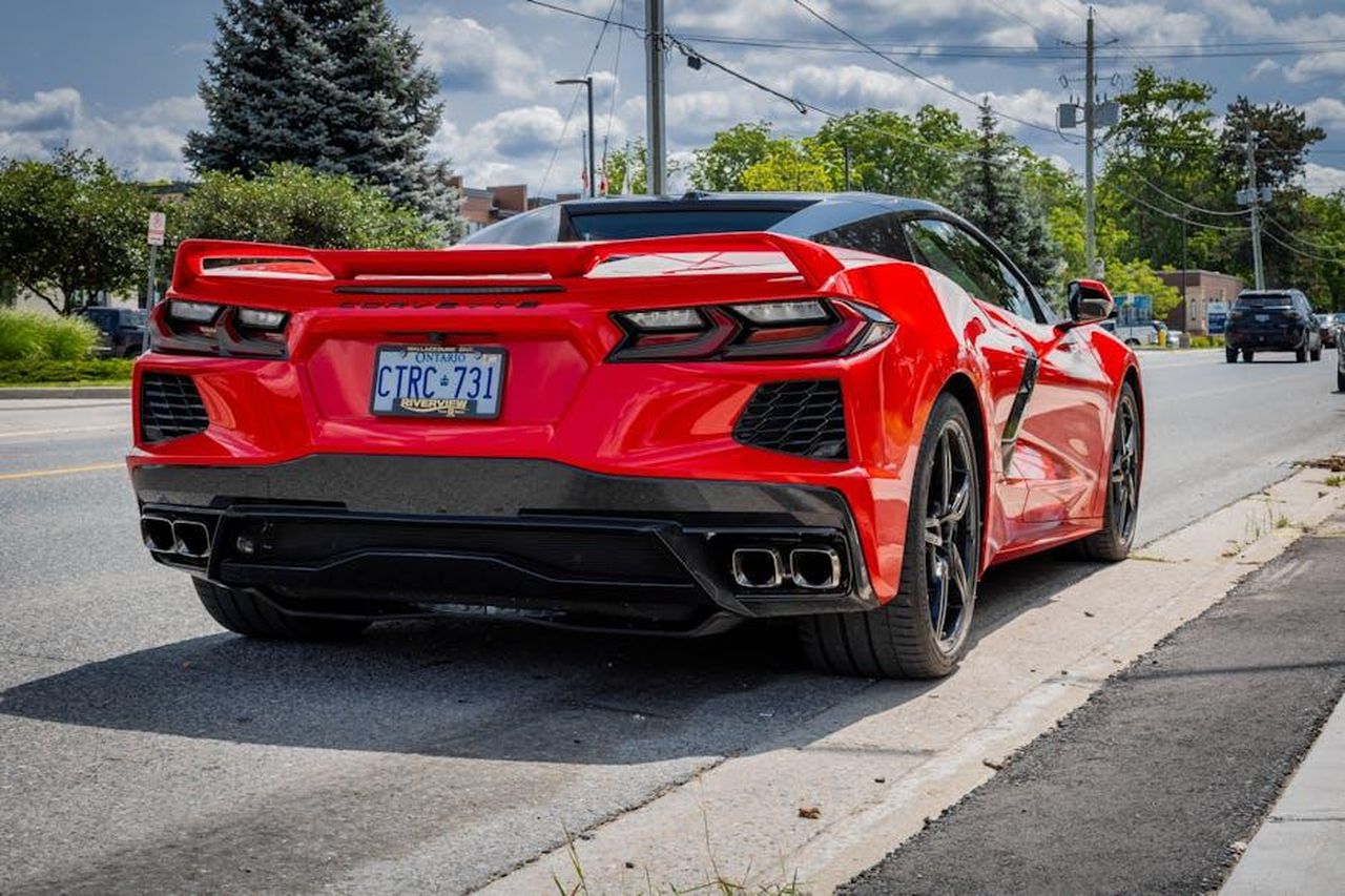 Brevetti_significativi_rilasciati_a_Toyota_nel_2024_petri1S3uH - Veicoli24 Source: Nicki Dick - pexels - Bright red sports car parked on a sunny suburban street with trees and power lines.