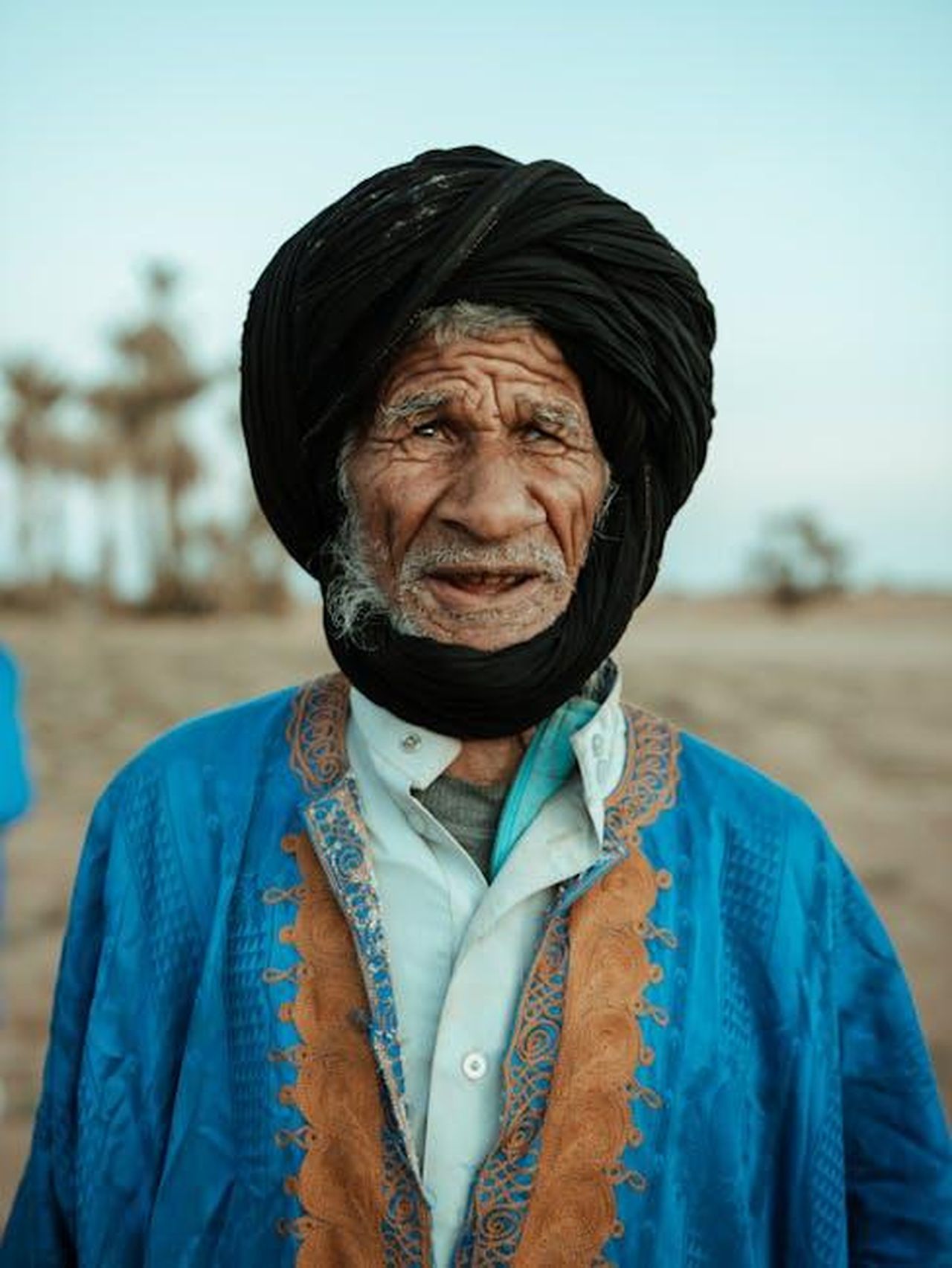 Collaborazione_internazionale_e_accesso_alla_storia_del_cinema_africano_QpF7Zfzg11 - Veicoli24 Source: JIMMY Art - pexels - A striking portrait of an elderly nomadic man in traditional attire in the Mhamid desert, Morocco.